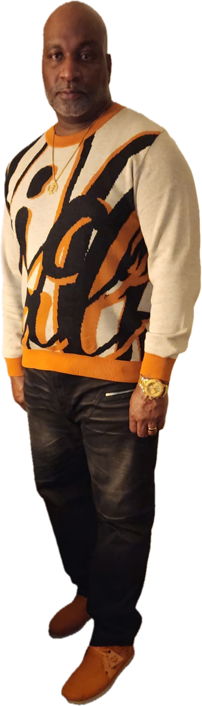 Man wearing a colorful sweater, black pants, and brown shoes, standing against a black background.