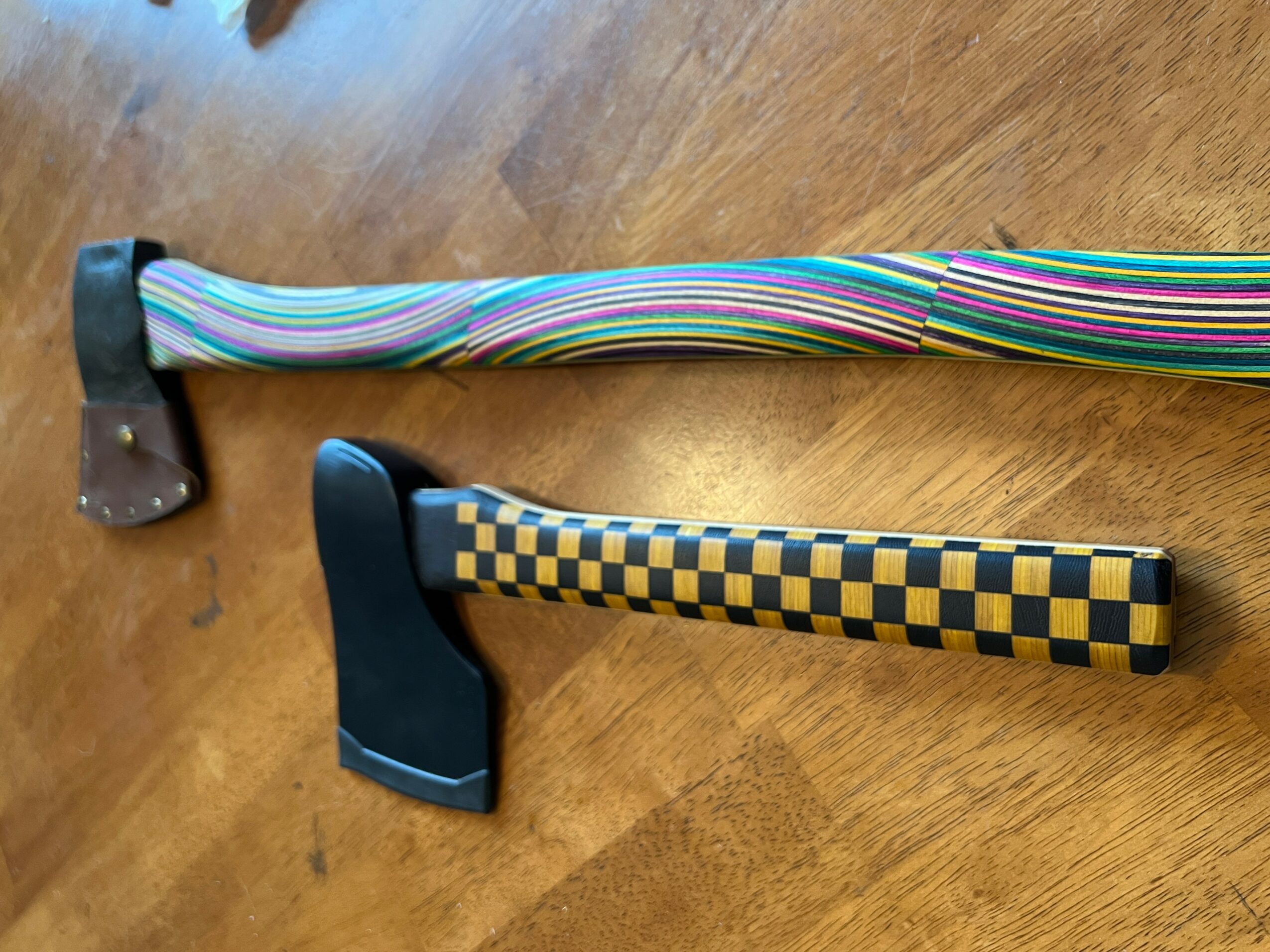 Two hammers with colorful handles on a wooden surface, one with a striped handle and the other with a checkered handle.