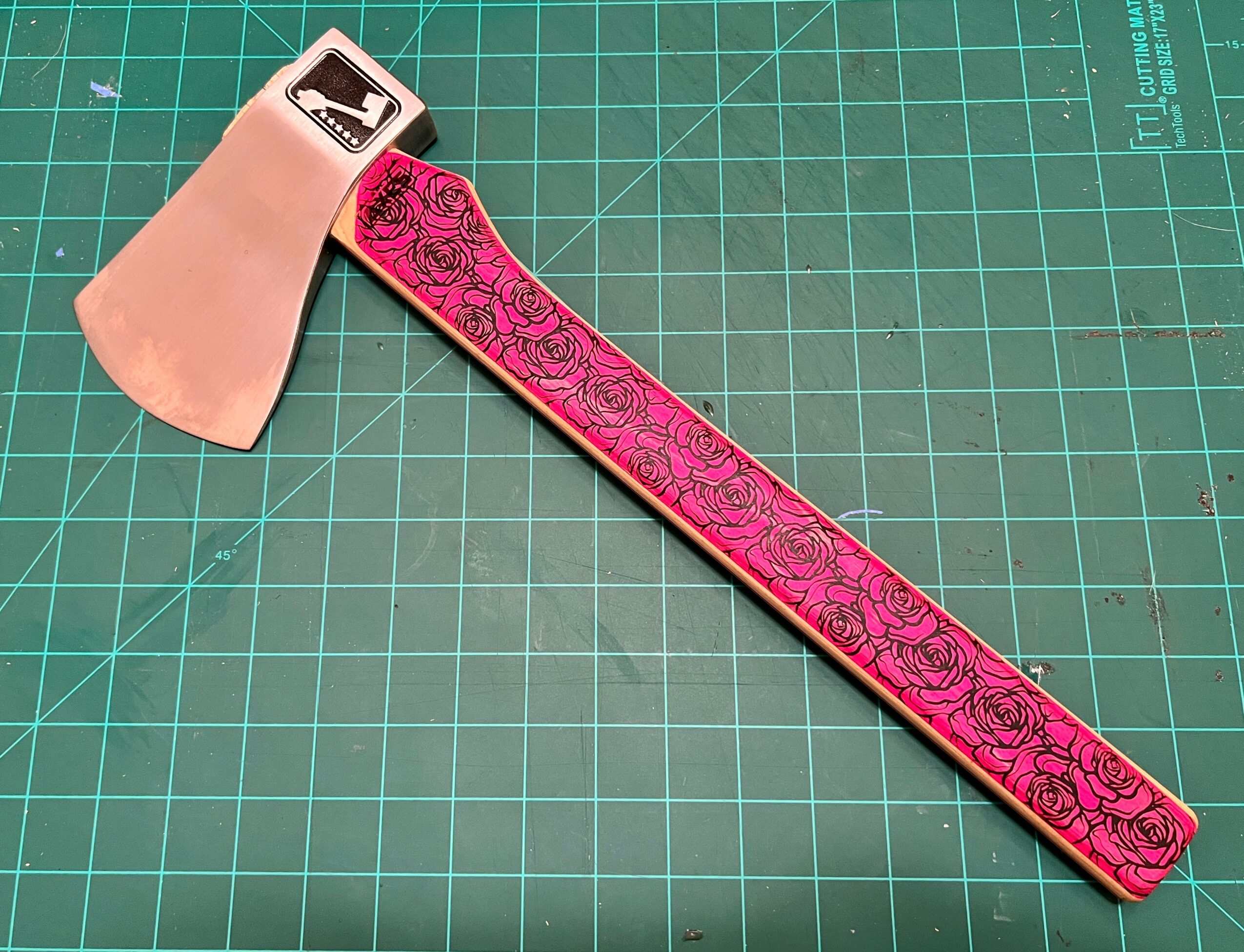 Pink and black patterned strap with a metallic buckle, placed on a green cutting mat.