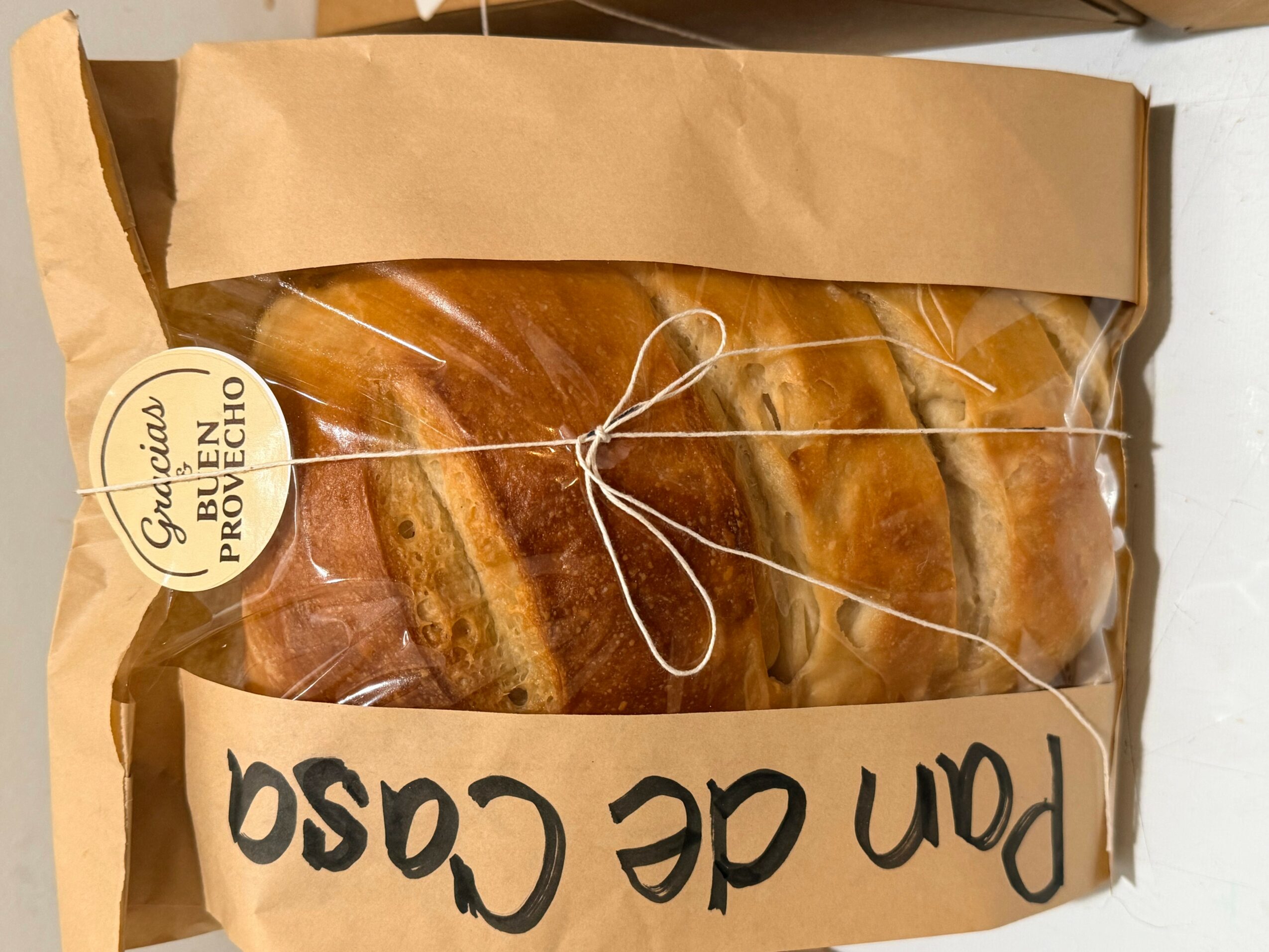 Packaged baked goods inside a clear plastic bag with a brown paper top, tied with a string, labeled