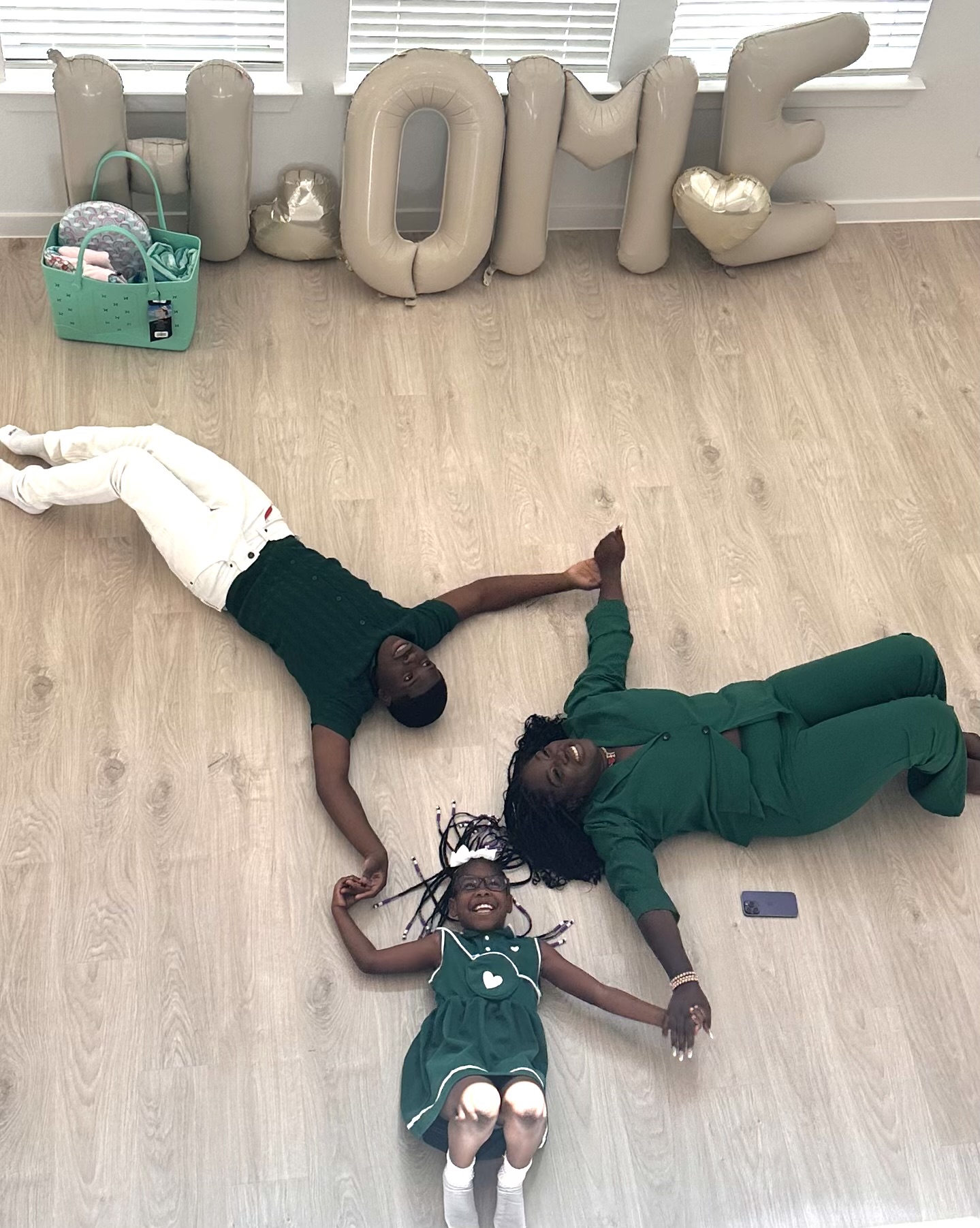 Three people lying on the floor holding hands, with large decorative letters spelling 'LOVE' in the background.