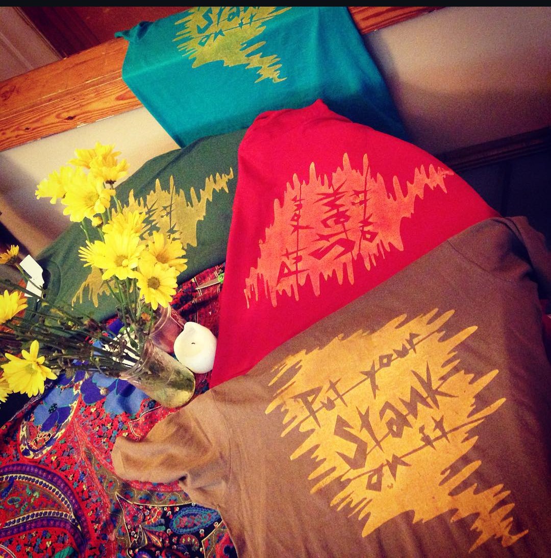 Colorful table with yellow flowers, patterned cloth, and T-shirts with graphic designs and text.