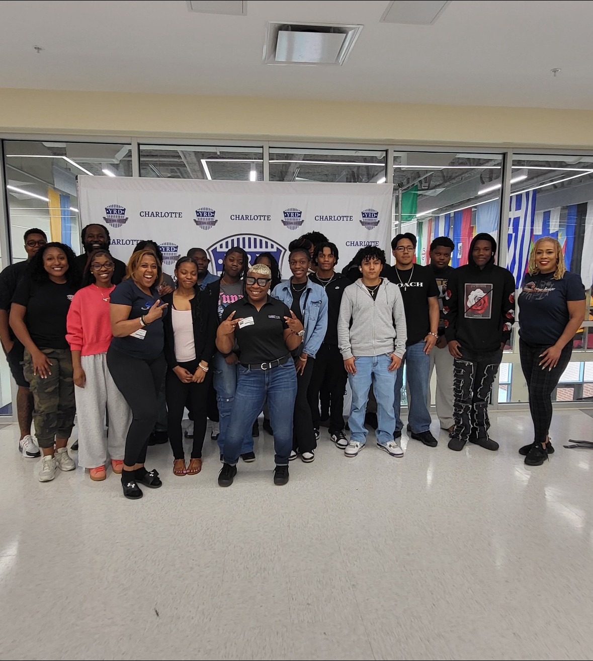 Group of people standing in front of a backdrop with logos, smiling and posing for a photo indoors.