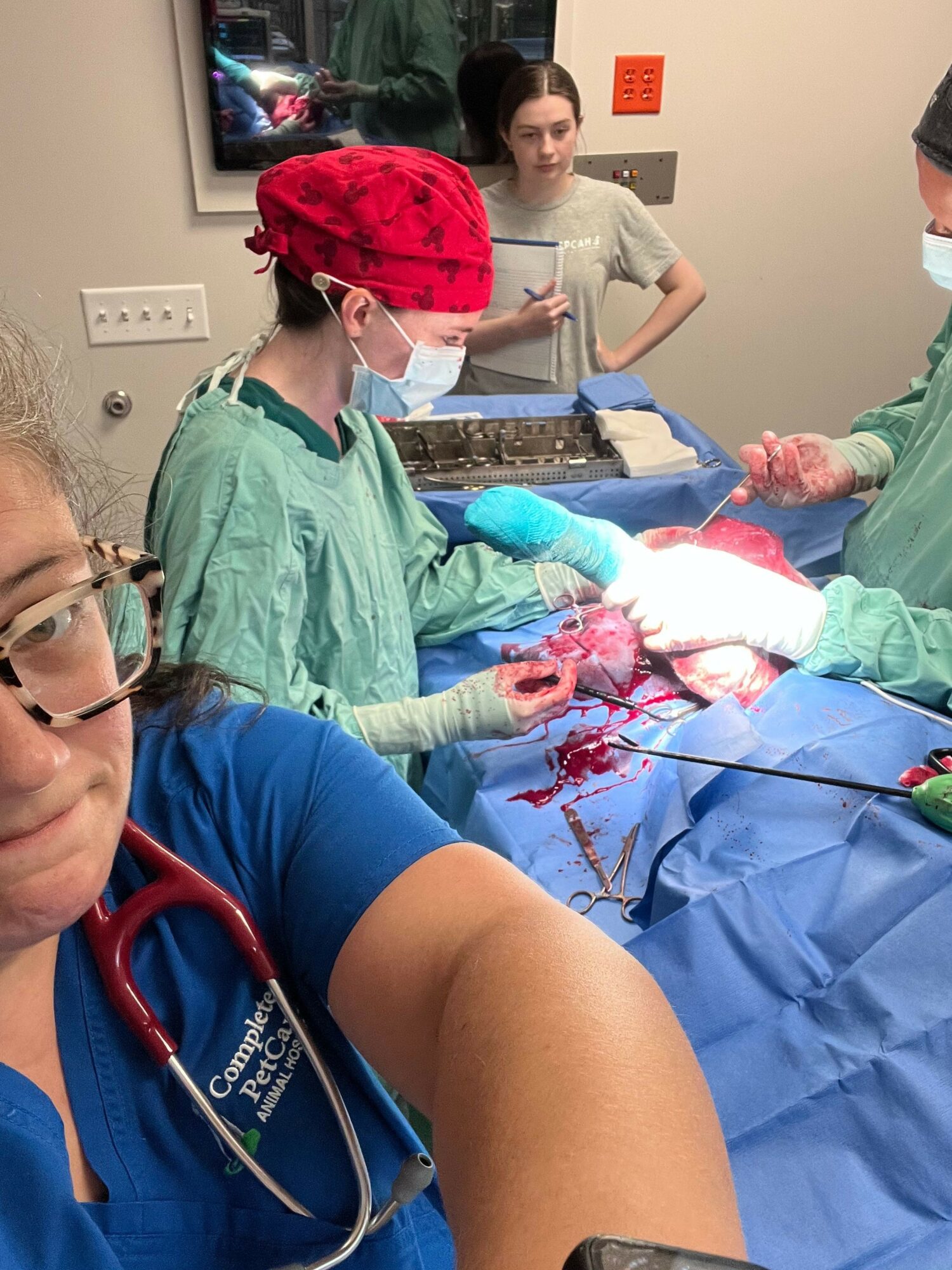 Medical team performing surgery with a person lying on an operating table, surrounded by medical staff and equipment.