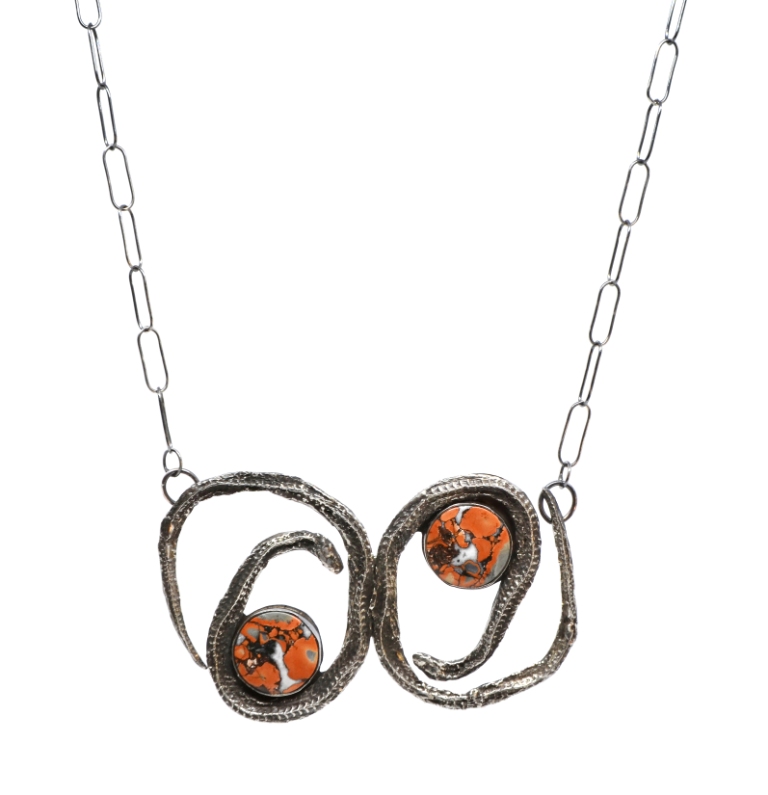 Necklace with two circular pendants featuring orange and black patterns, connected by a chain.
