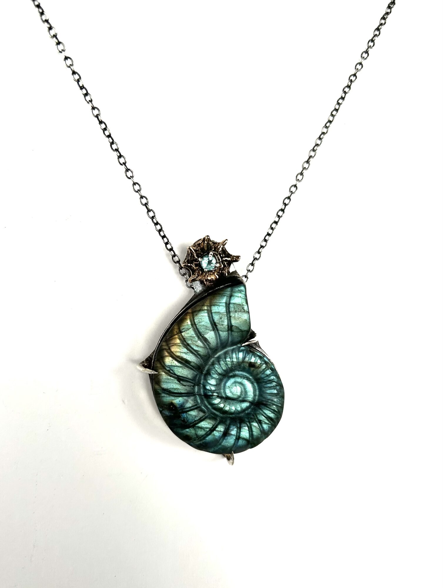 A necklace with a spiral shell pendant and a small star-shaped charm with a gemstone, on a white background.