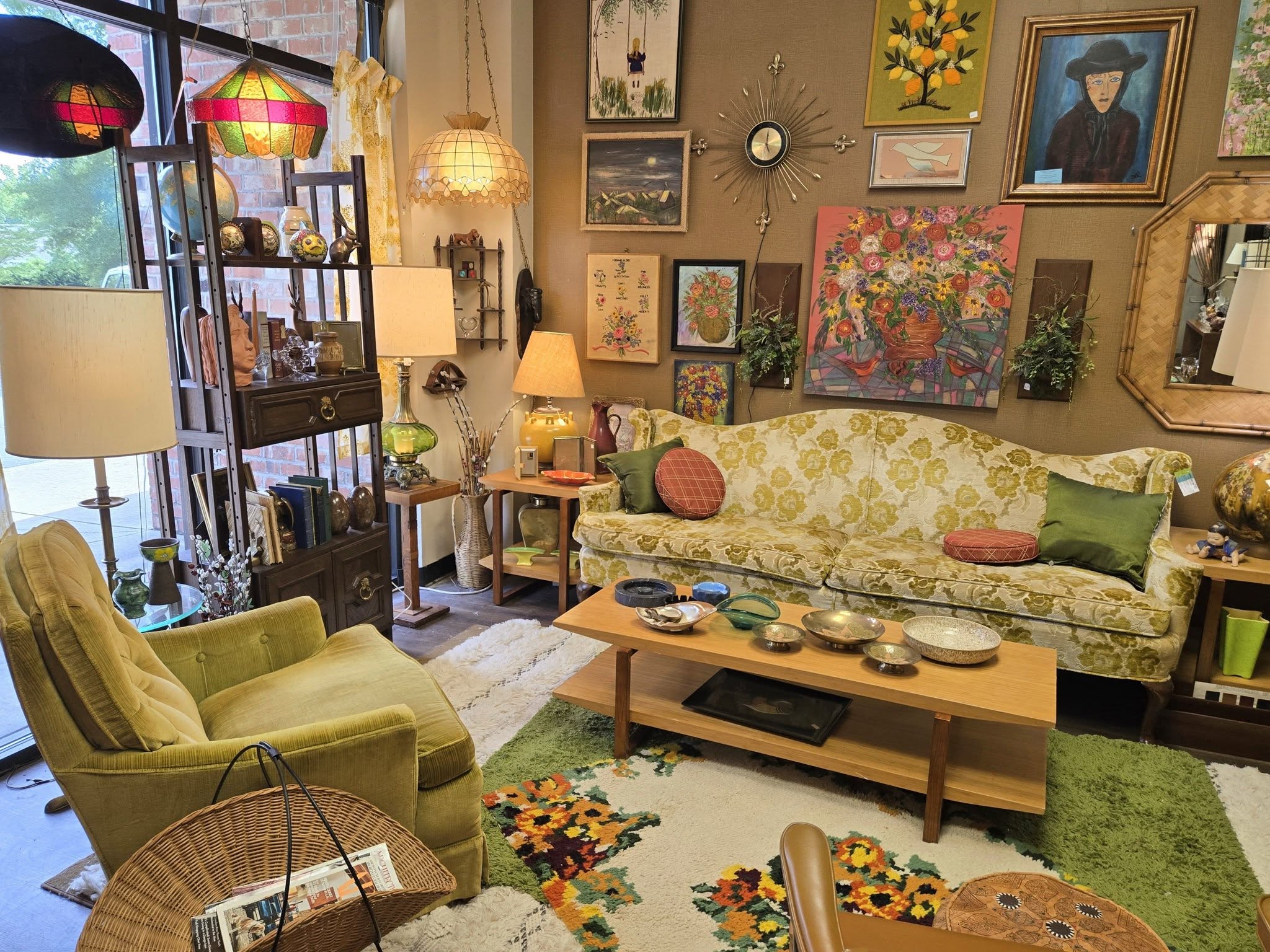 Living room with colorful furniture, artwork, and decorative items, including a sofa, armchair, coffee table, and various lamps.