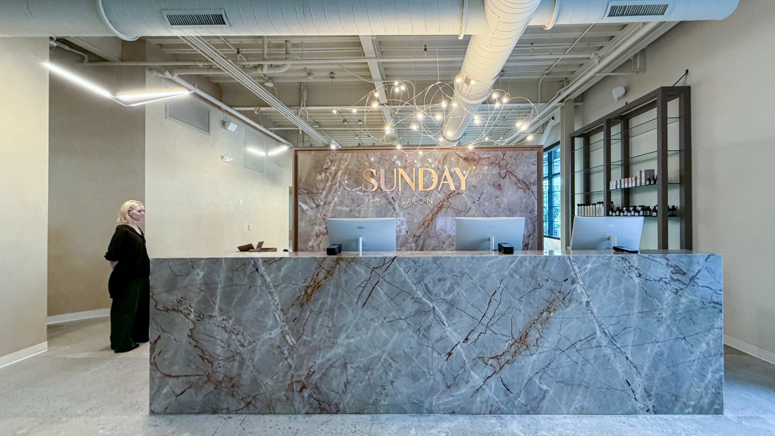 Reception area with a marble counter, a person on the left, and a wall with 'SUNDAY' sign behind the counter.