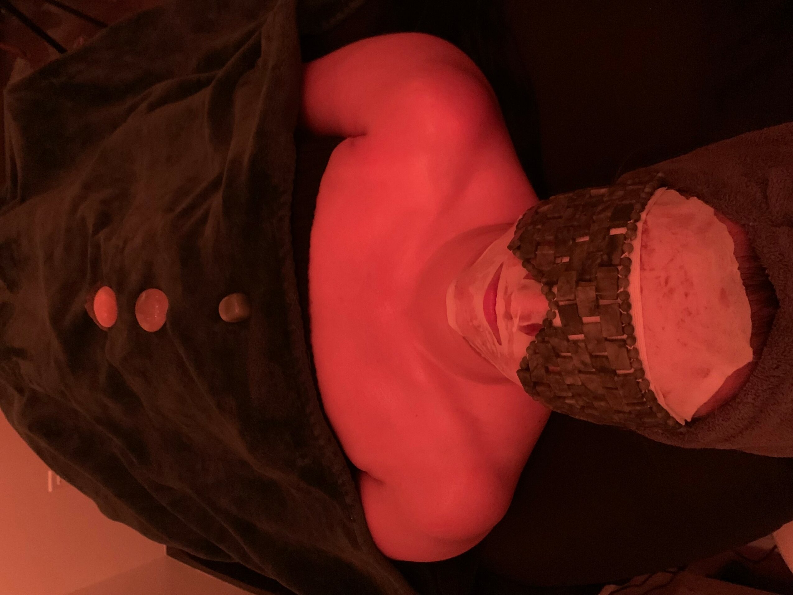 Person lying down with legs raised, wearing dark clothing and a sock, in a dimly lit room.