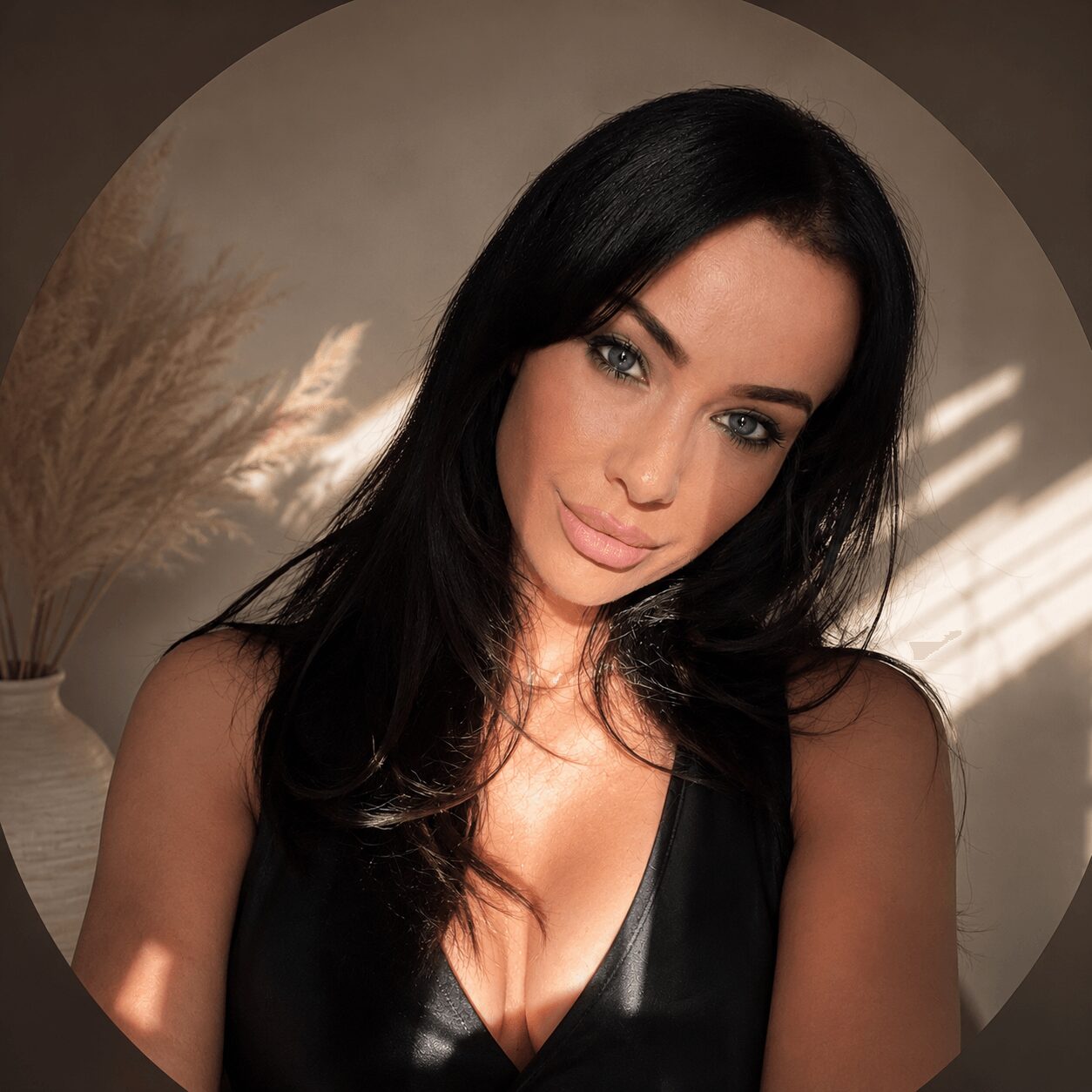 Woman with long black hair and blue eyes, wearing a black top, in a well-lit room with a plant in the background.
