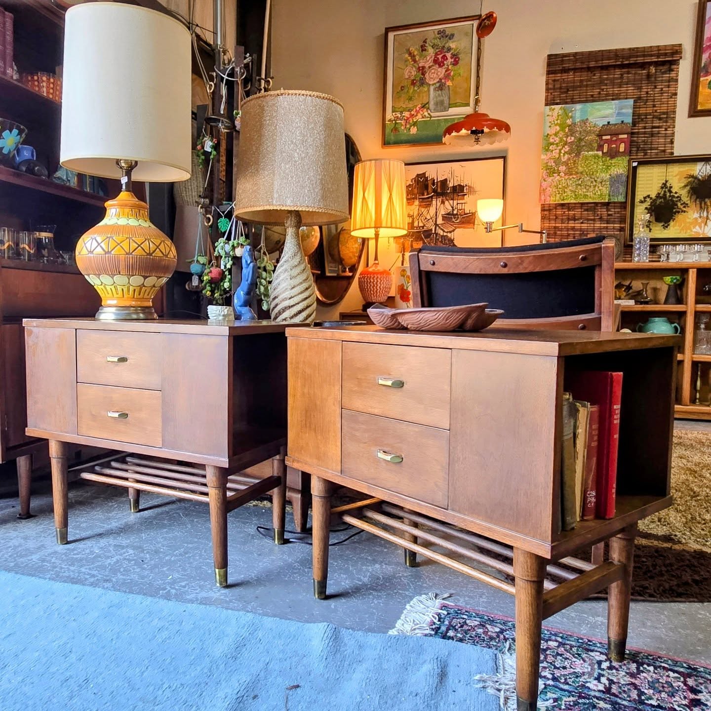 Two wooden sideboards with lamps and decorative items in a room with artwork and furniture, viewed from the front.