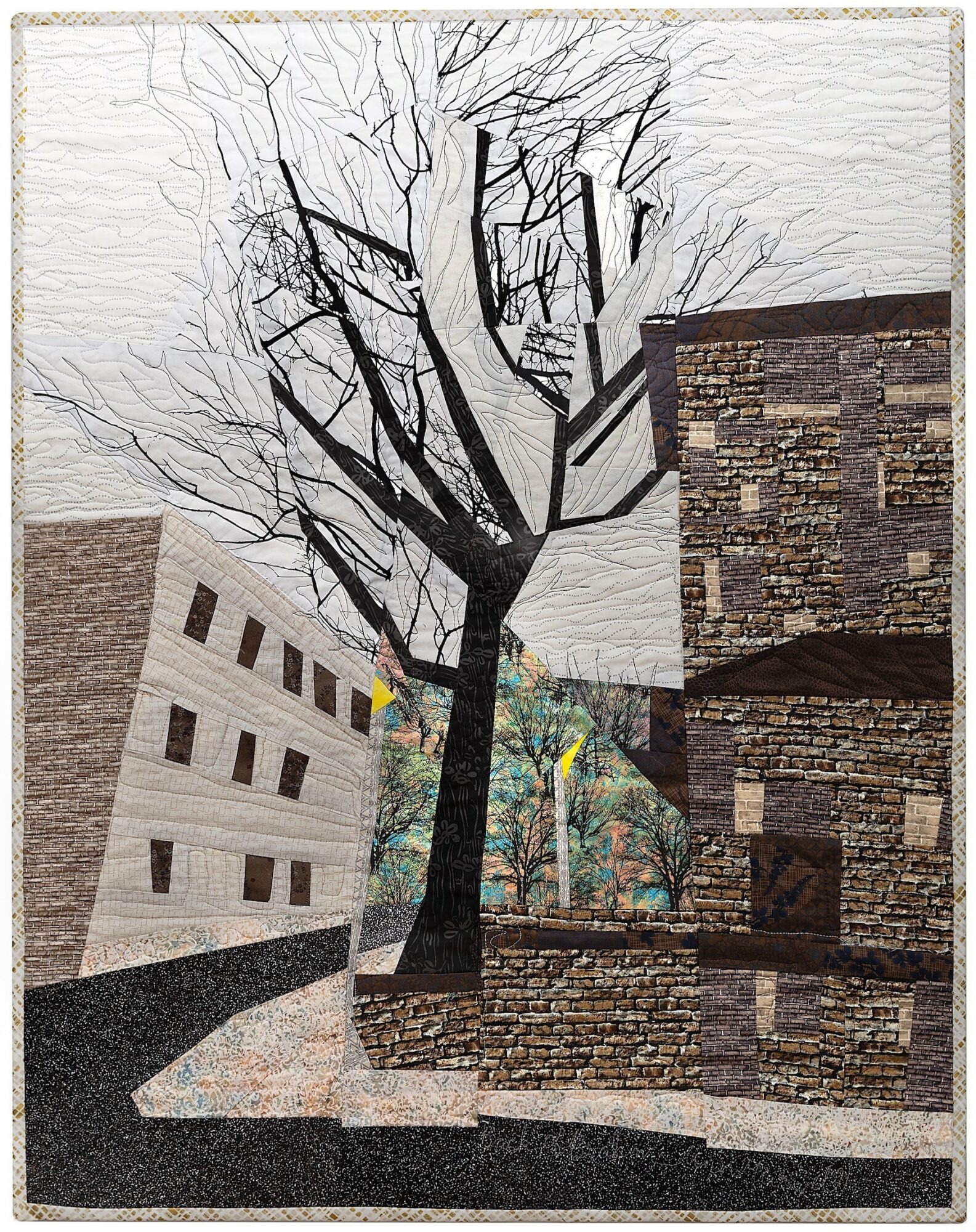 A leafless tree between buildings, with a cloudy sky in the background, and a colorful object near the tree.