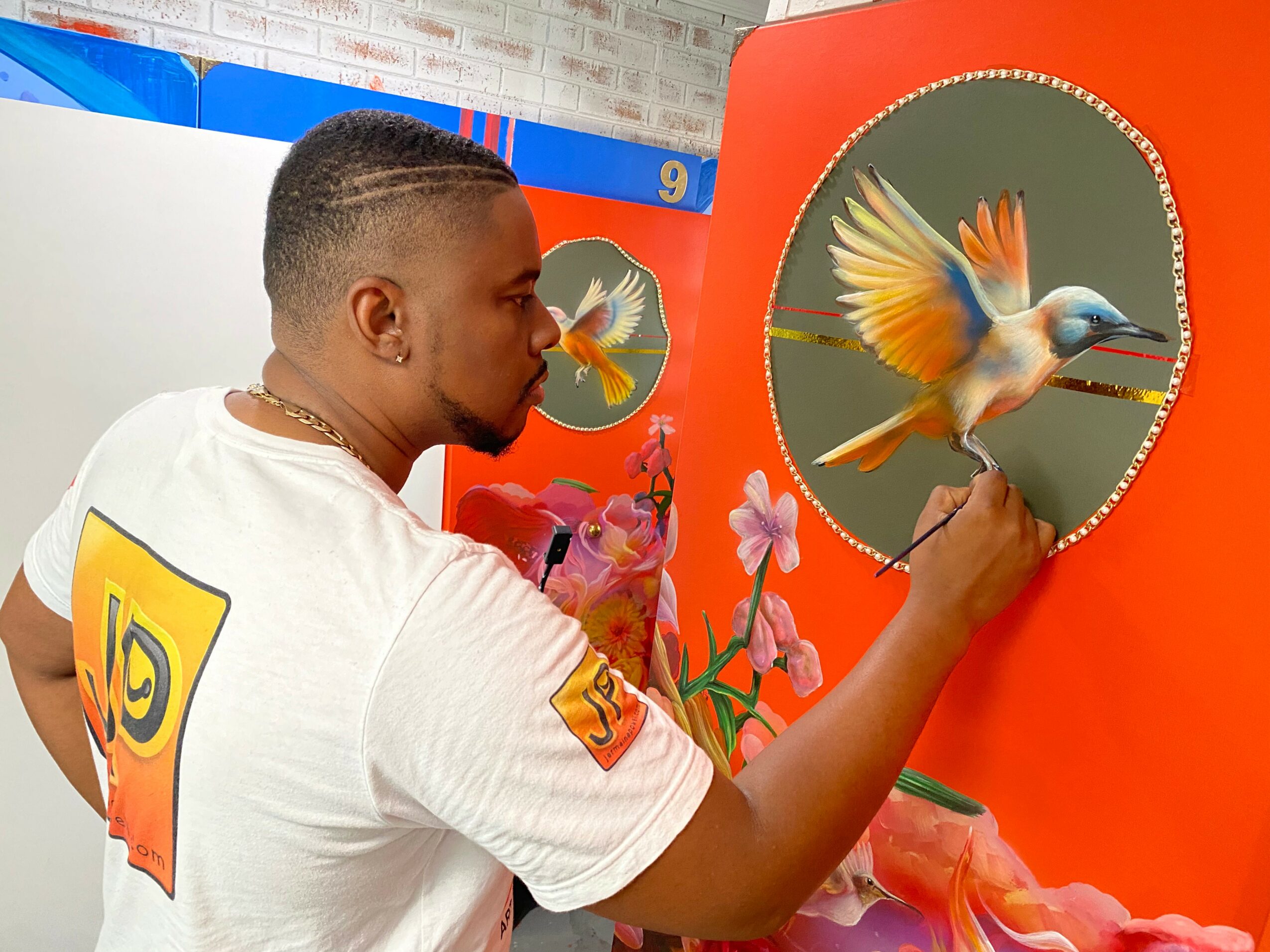 Person looking at a bird in a circular mirror, with pink flowers nearby, against an orange background.