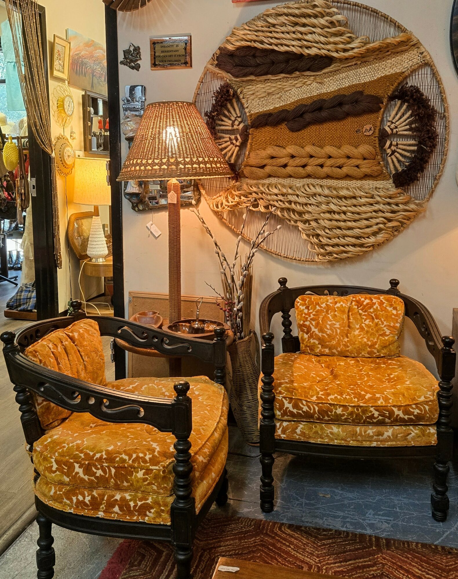 Interior with two vintage-style chairs with yellow velvet cushions, a wooden side table, a lamp, and wall art, in warm lighting.