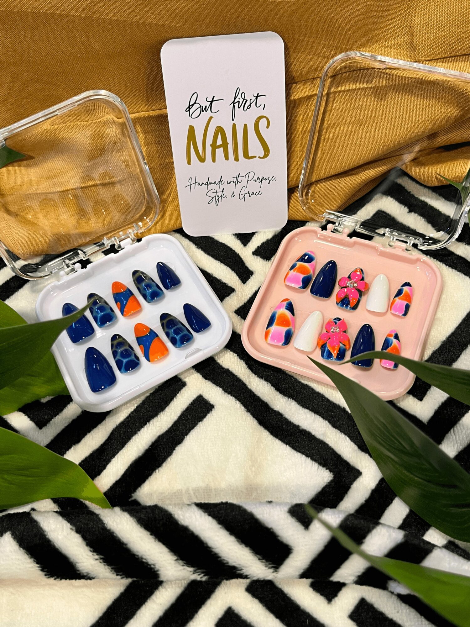 Two open cases of colorful nail art designs on a zebra-patterned fabric, with a sign reading 'art first NAILS' in the background.