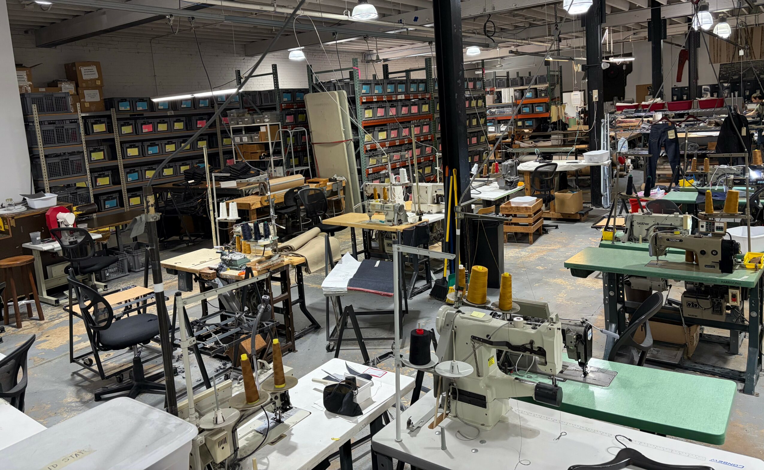 Workshop with sewing machines, tables, and shelves filled with supplies and materials.