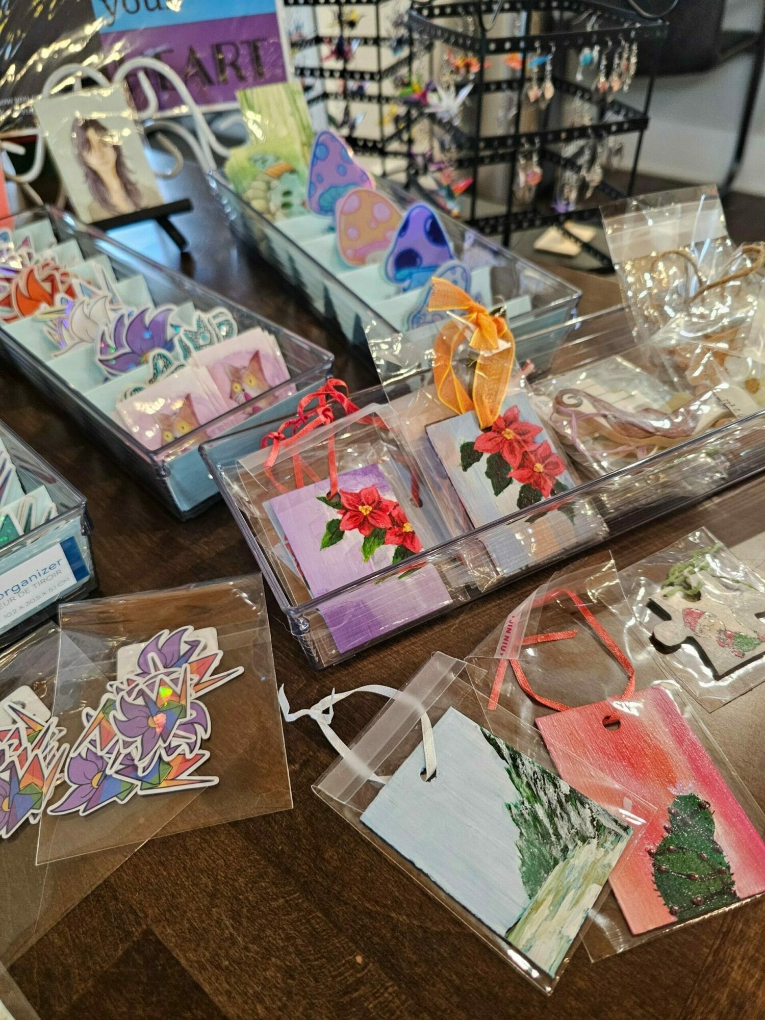 Various colorful paper crafts and decorations on a wooden surface, including flowers, butterflies, and geometric shapes.