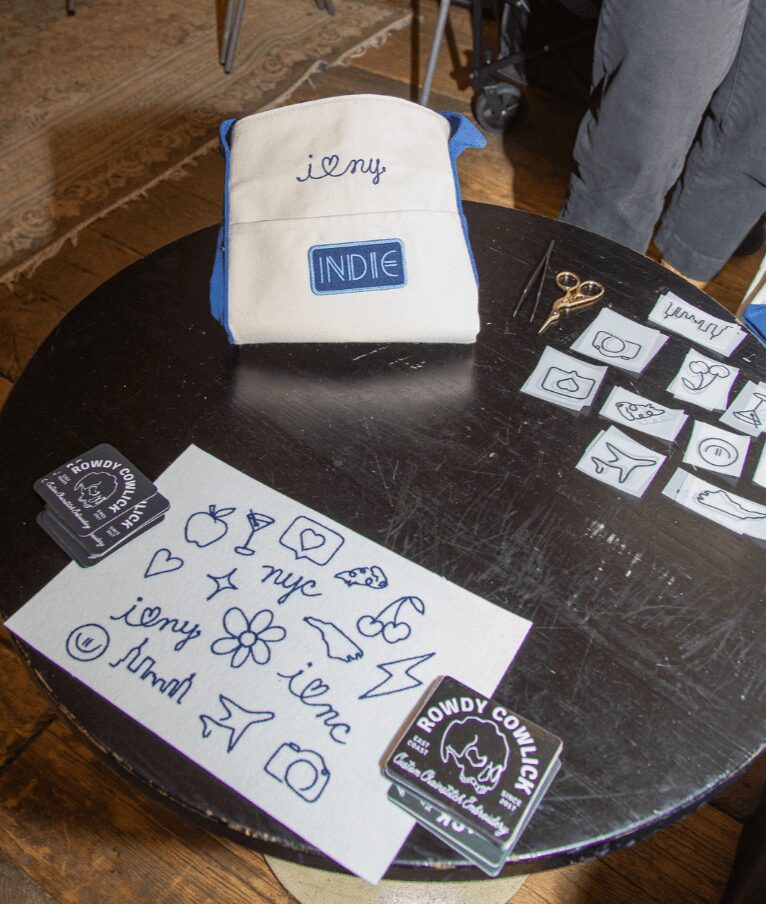 Black round table with white bag, paper with drawings, and small cards with icons, in a room with wooden floor.