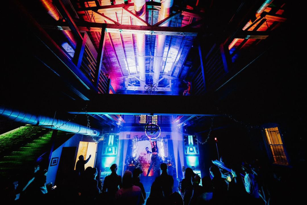 Concert scene with colorful lights, silhouettes of people dancing, and a stage with performers, vibrant atmosphere, 20 words.