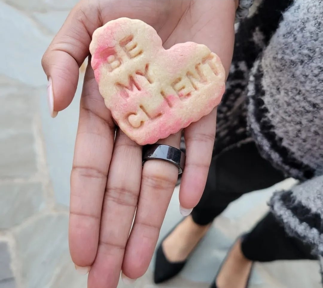 Person holds a heart-shaped cookie with the words 