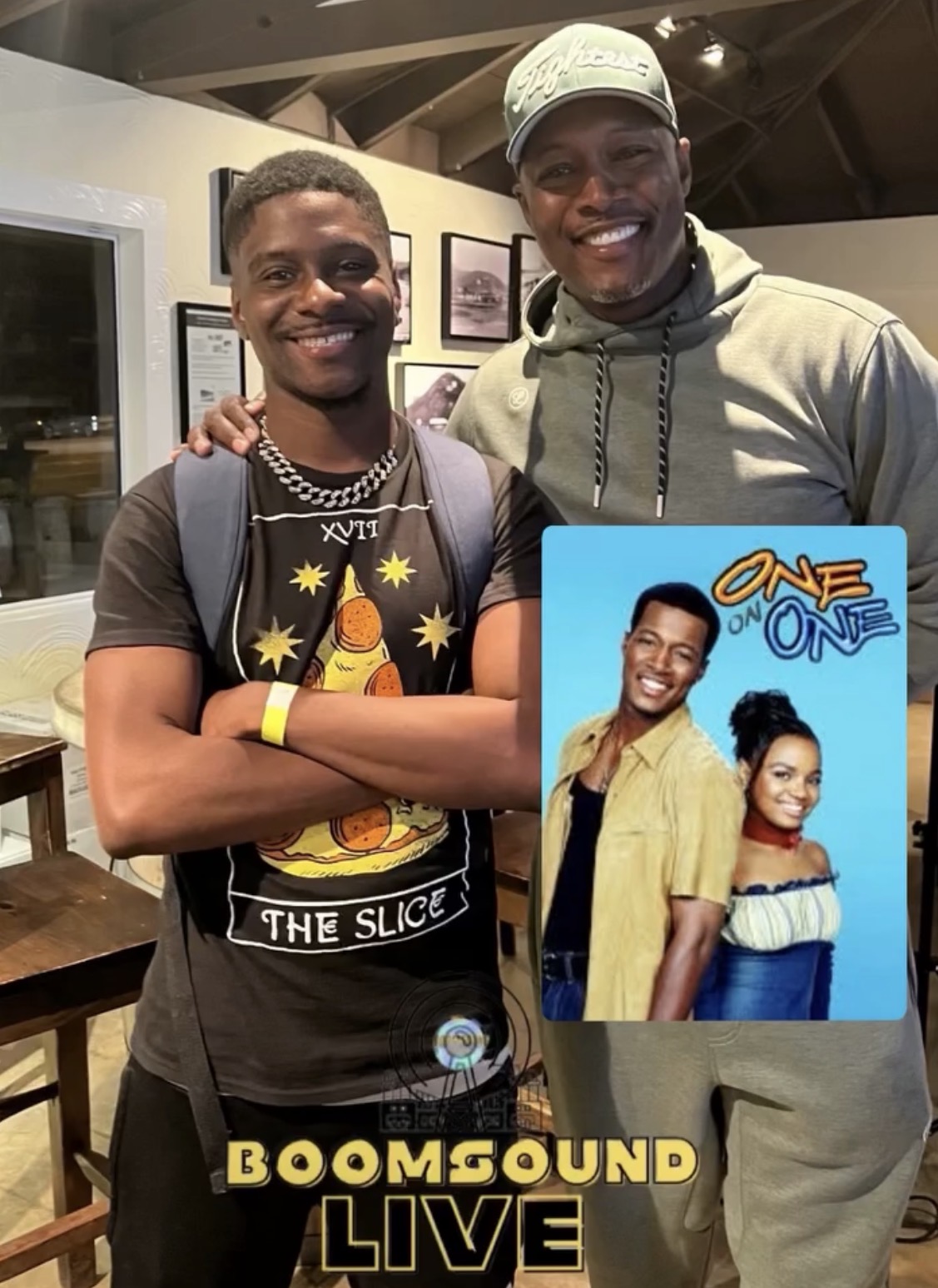 Two smiling men standing indoors, one with a backpack, and a promotional poster for BoomSound Live featuring two people, one in a yellow shirt and the other in a striped top.