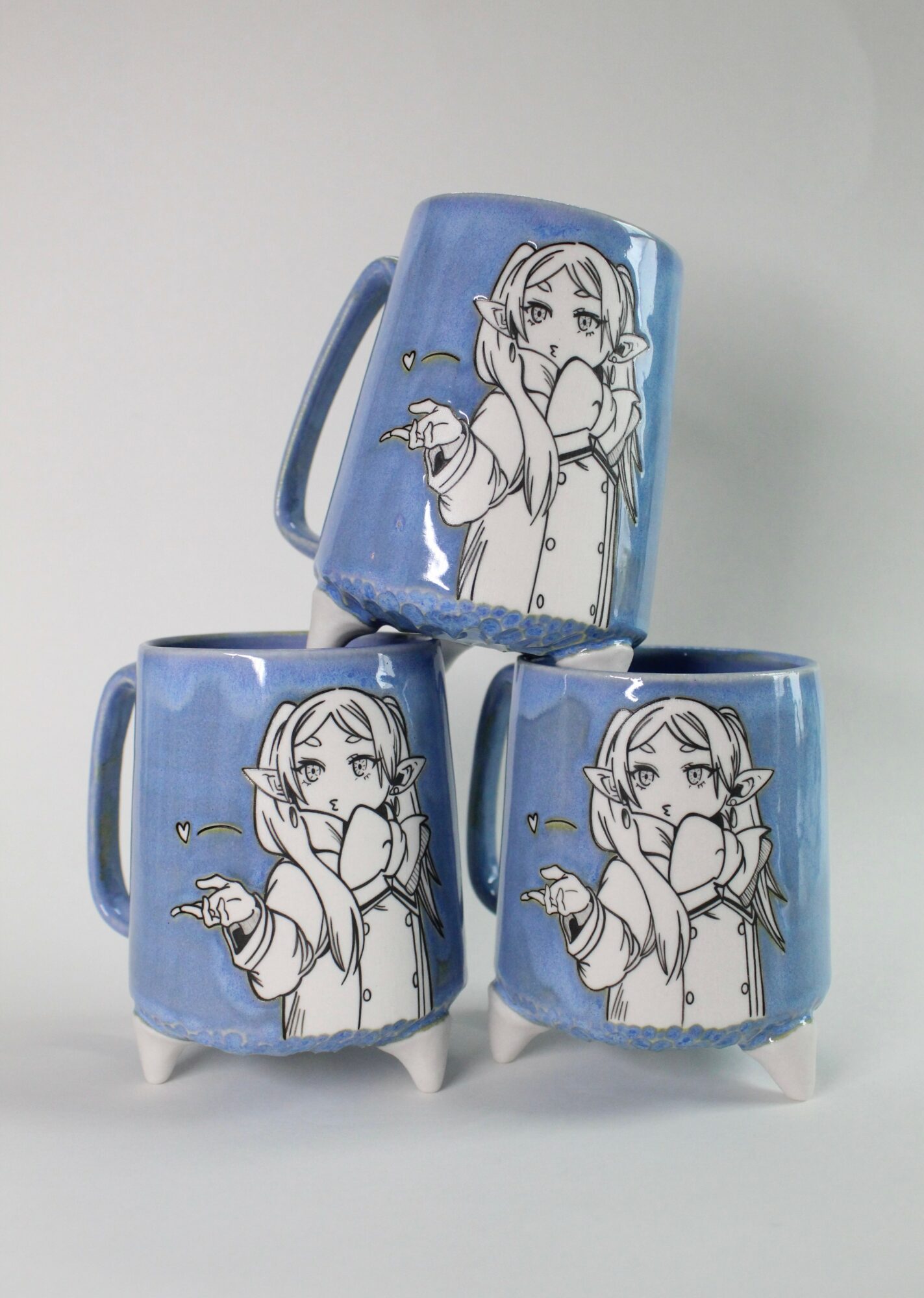 Three blue mugs with a black and white illustration of a girl with glasses, pointing, stacked on a plain background.
