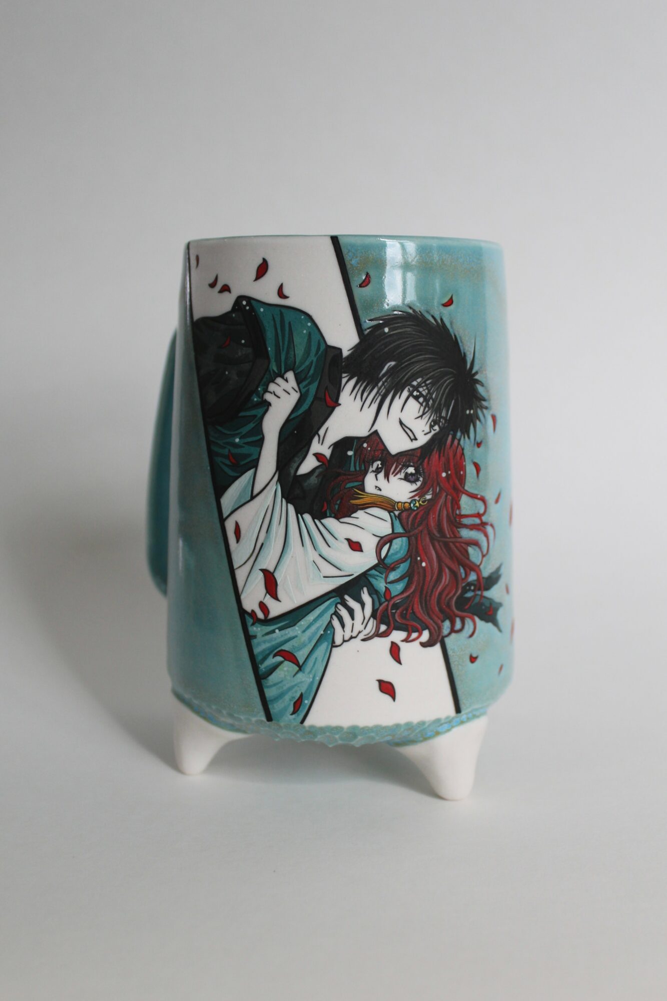 A ceramic vase features anime-style artwork of a person with black hair and a girl with red hair, surrounded by falling petals.