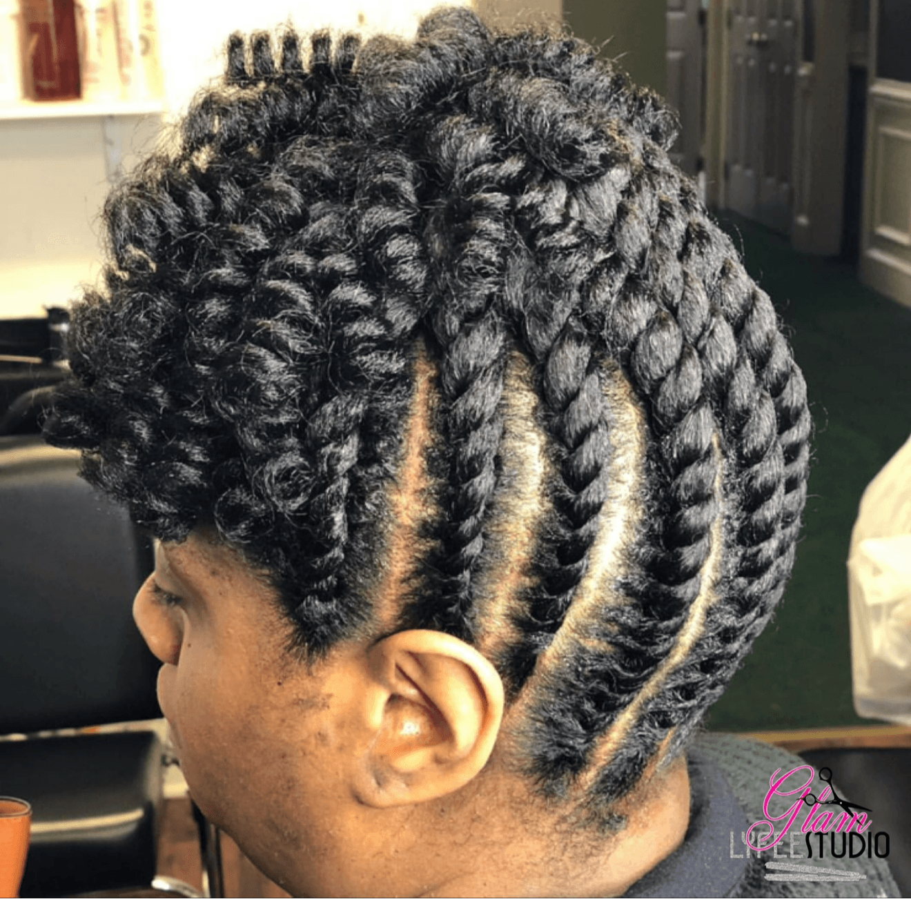 Side view of a person with styled natural curly hair and cornrows, in a salon setting.