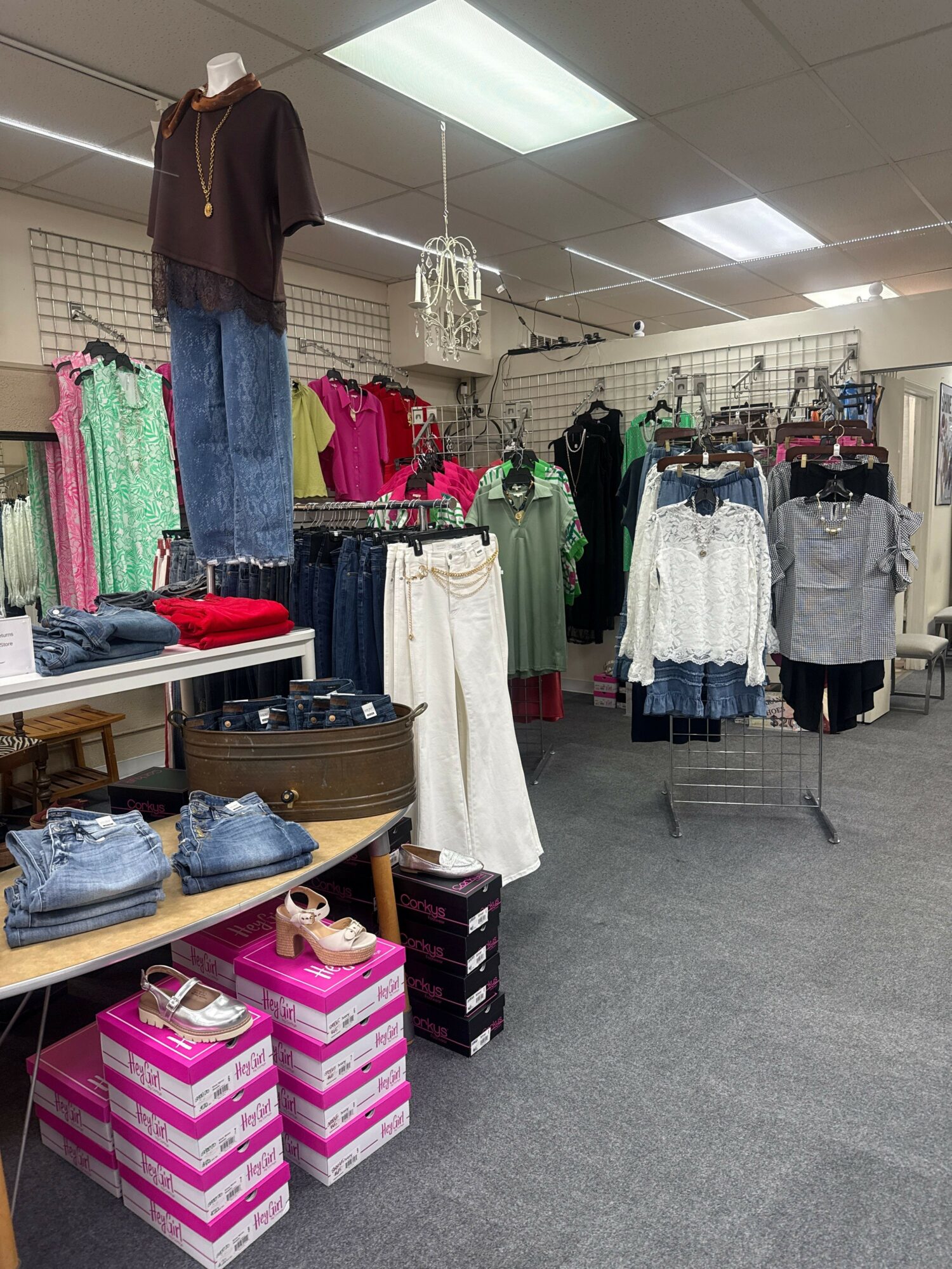 Clothing store interior with racks of clothes, a mannequin, and pink and white boxes on the floor.