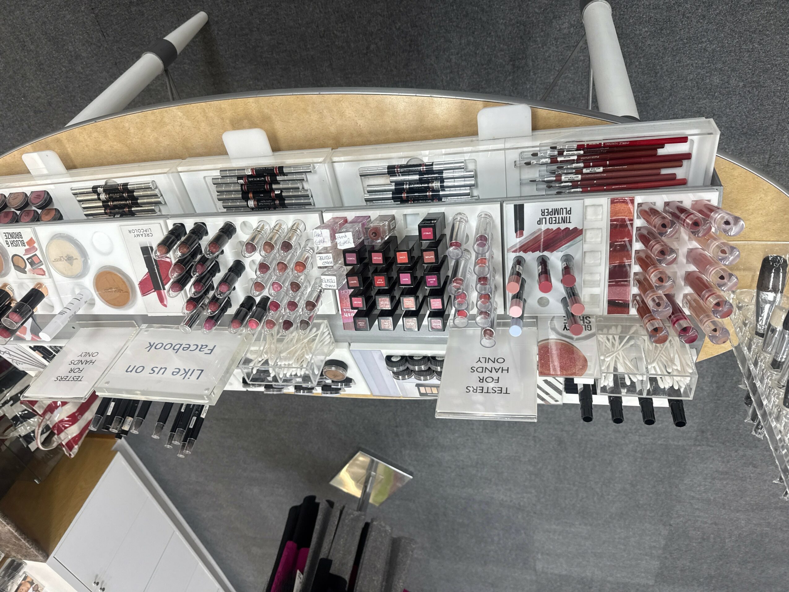 Display of various lipsticks and makeup products on a table, viewed from above.