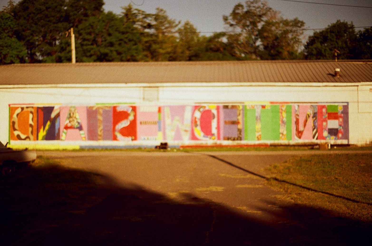 Colorful mural spelling 'LOVE' on a wall with trees and sky in background.