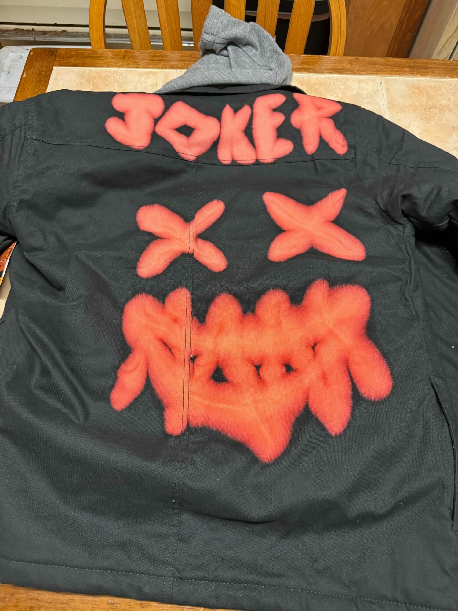 Black fabric with red spray-painted text and symbols, including X marks and Chinese characters, on a wooden surface.