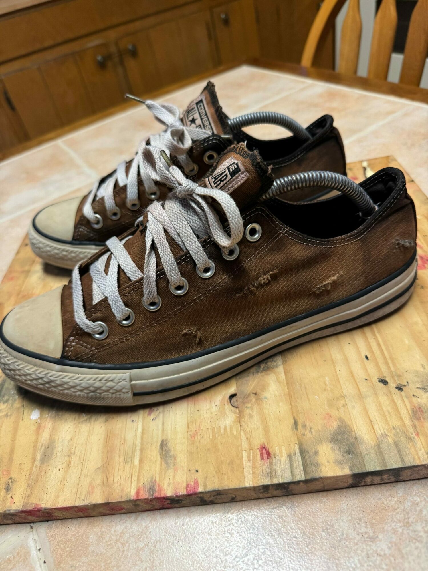 Pair of brown high-top sneakers with white laces on a wooden surface.