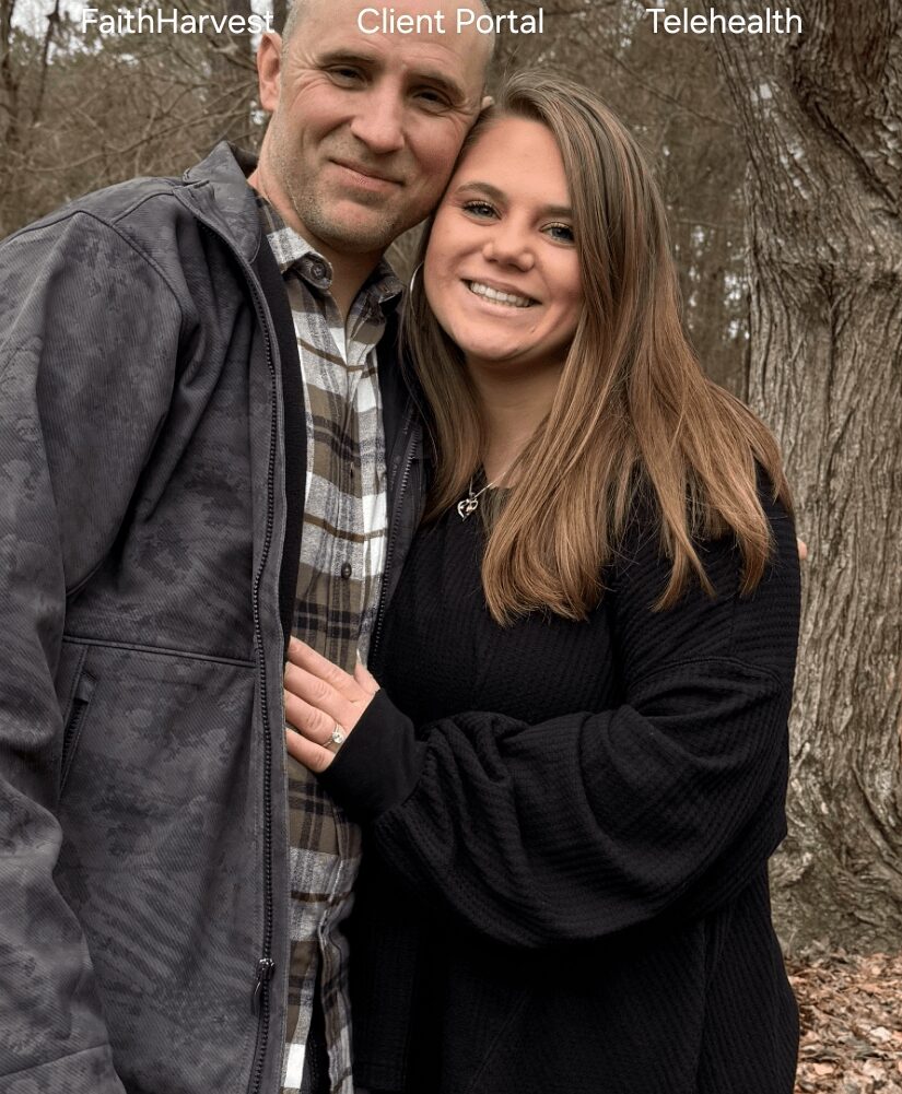 A man and a woman smiling outdoors with trees in the background.