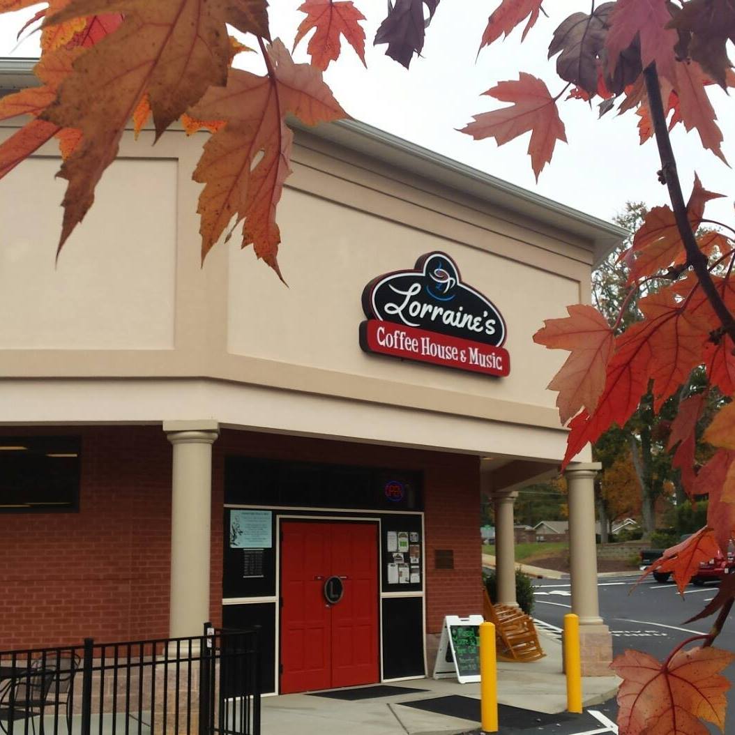 Exterior of Lorraine's Coffee House & Music with red door, columns, and autumn leaves in foreground.