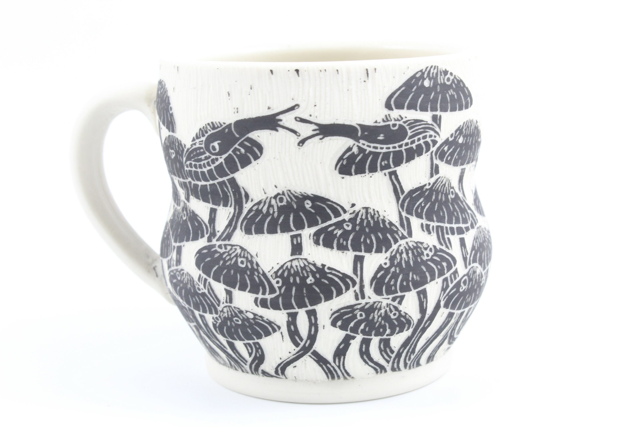 White mug with black illustrations of mushrooms and shrimp, with a handle on the left side.