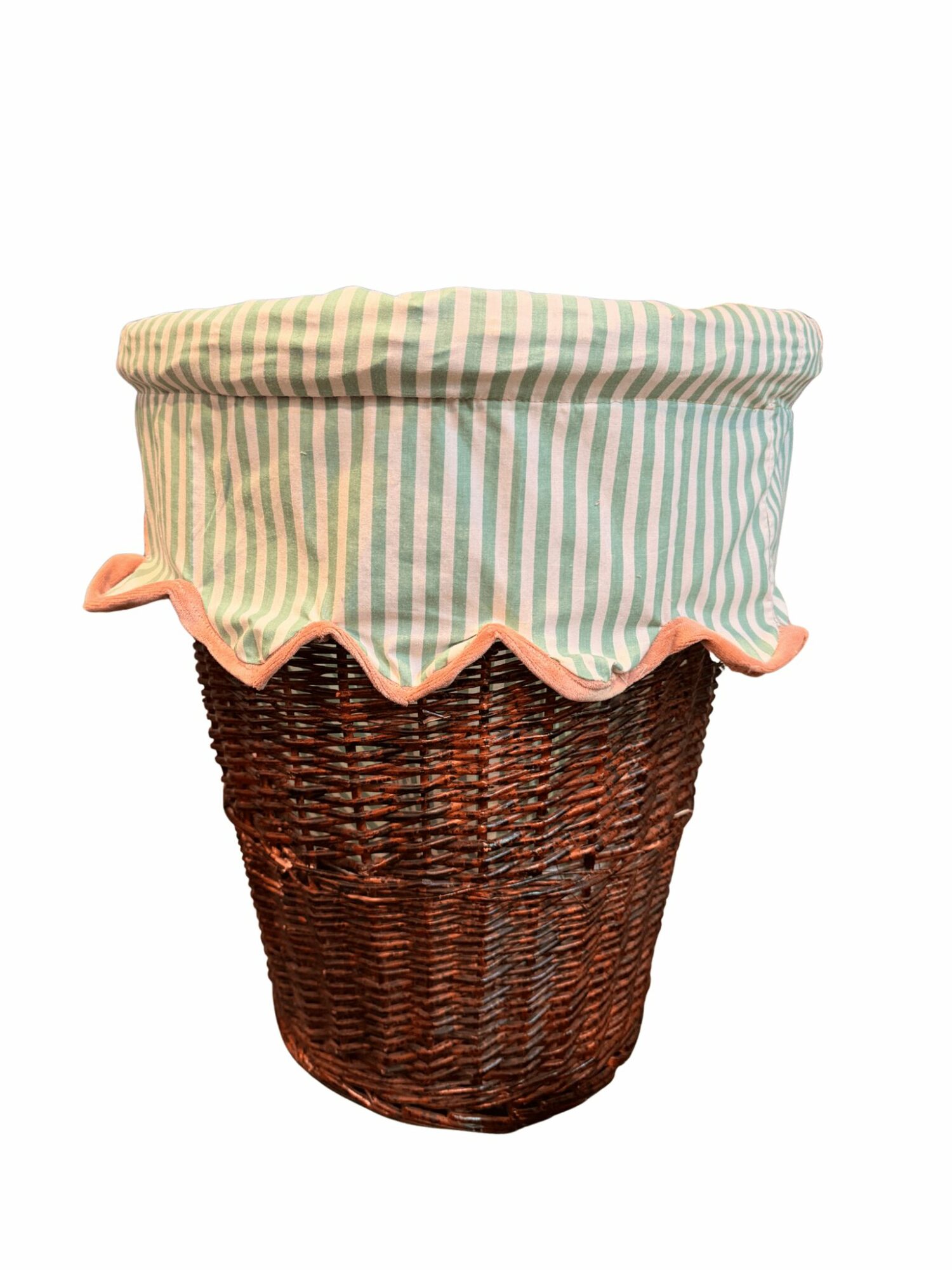 Wicker basket with a fabric cover featuring pastel green, pink, and white stripes and a ruffled edge.