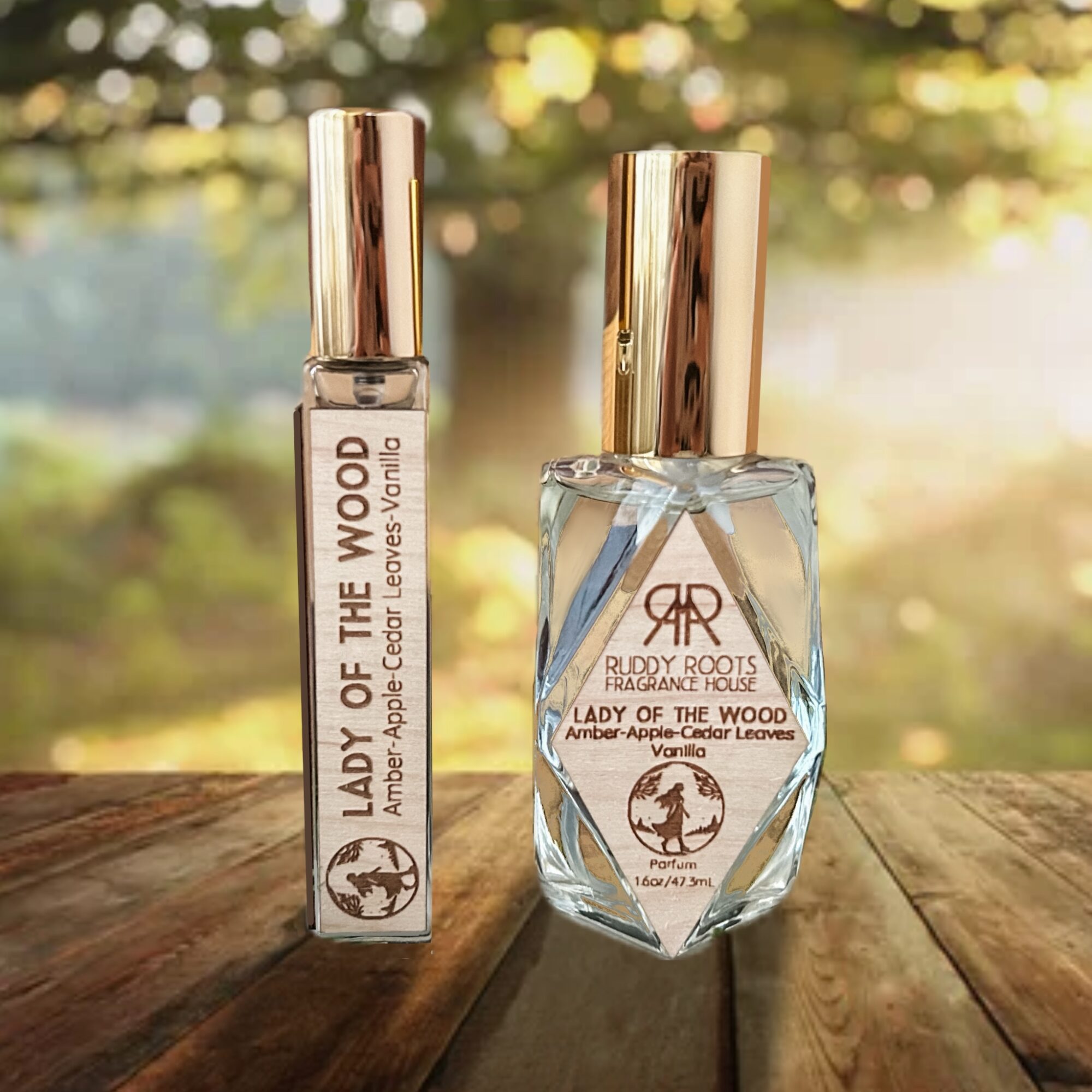 Two perfume bottles on a wooden surface with a blurred outdoor background, one tall and rectangular, the other rounded, both with gold caps.