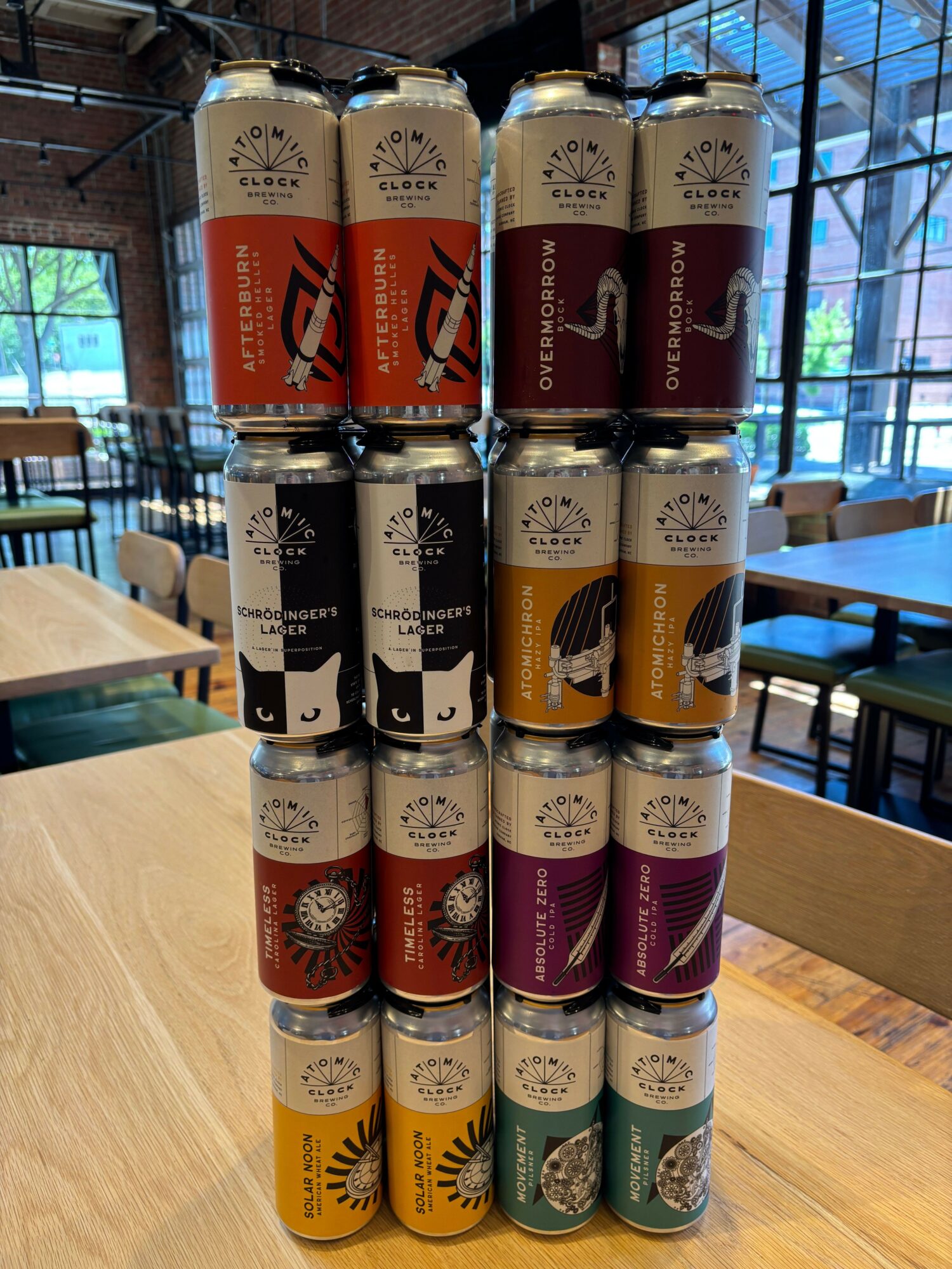Multiple cans of beverages arranged on a table, with a window and interior space in the background.