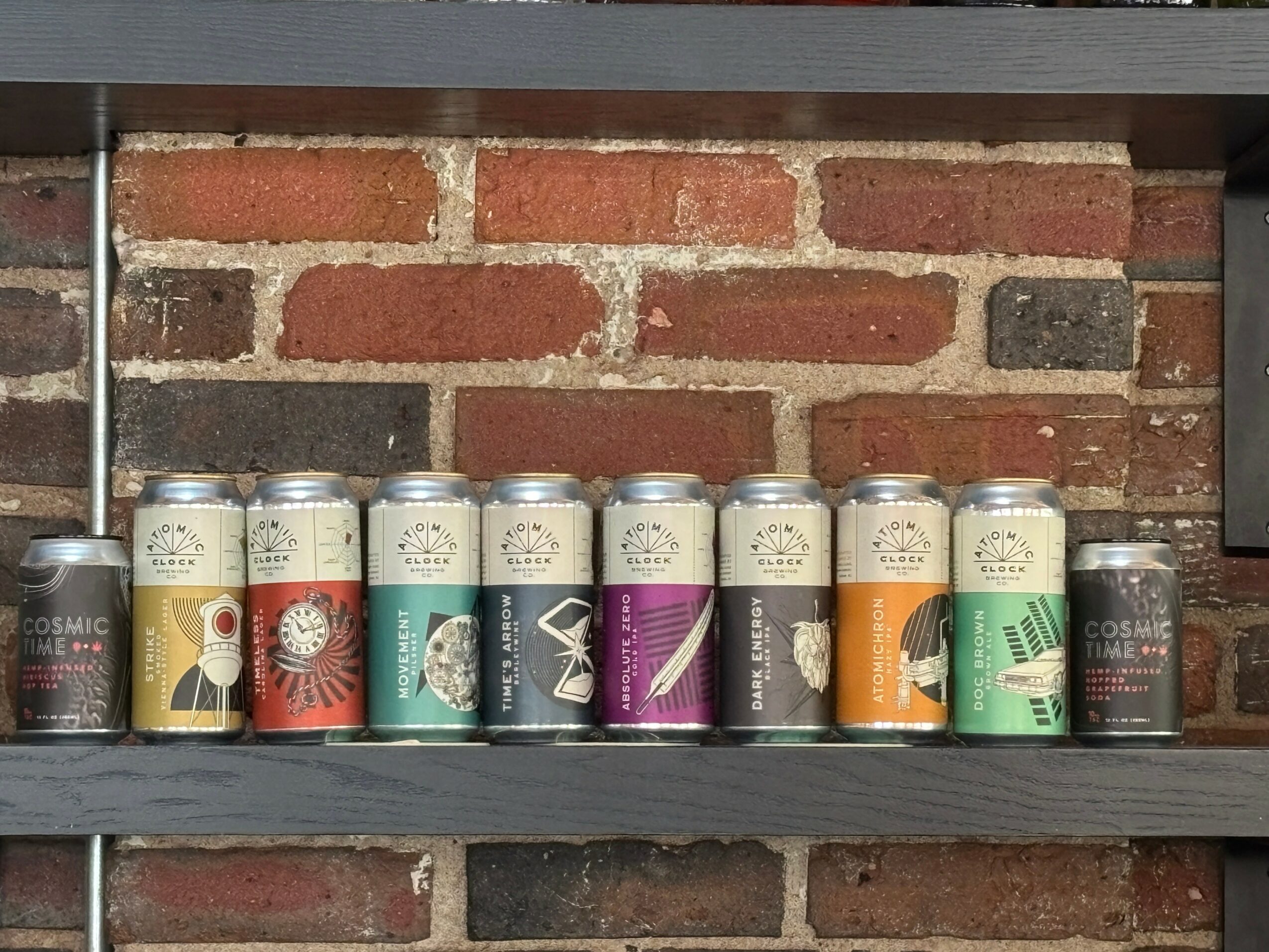 Shelf with cans of different colors and designs against a brick wall background.