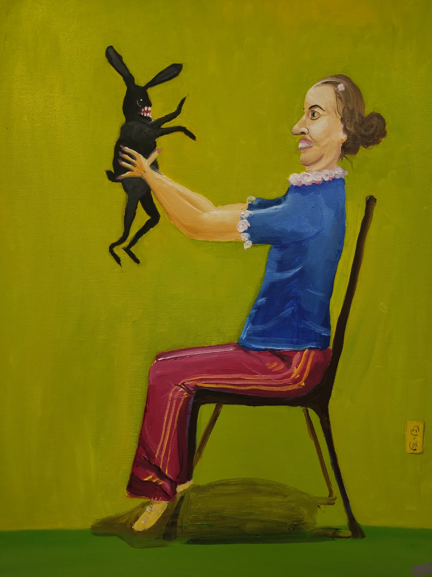 Woman sitting on a chair holding a black rabbit with long ears against a green background.