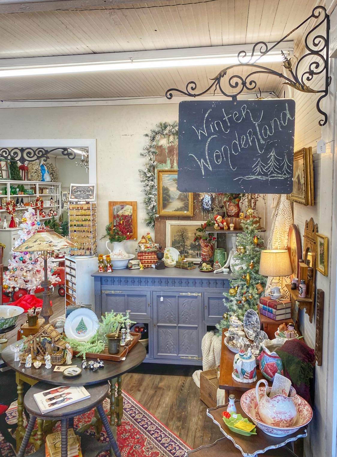 Indoor scene with a blue cabinet, decorated for winter, surrounded by various ornaments, framed pictures, and a chalkboard sign reading 'Winter Wonderland'.