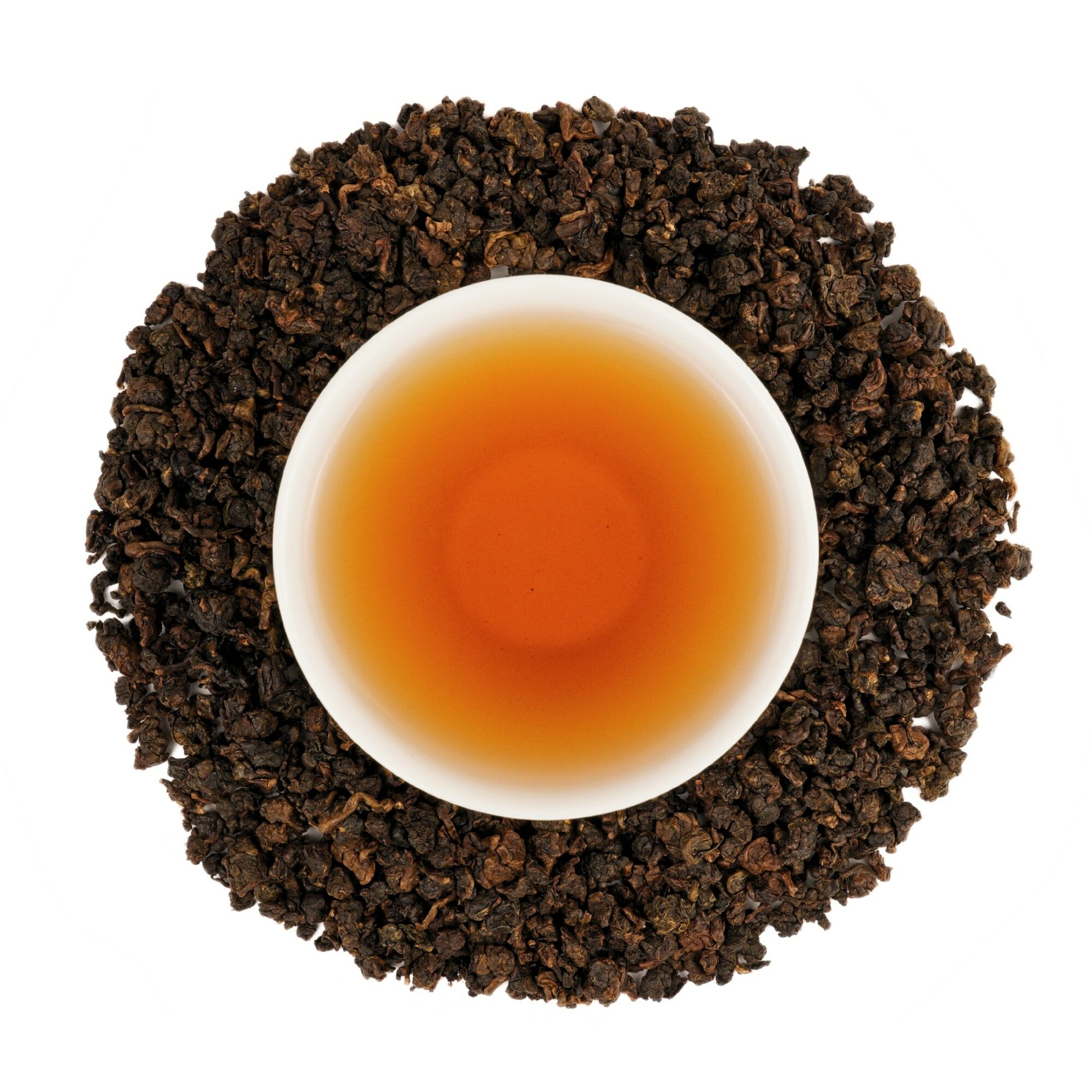 Top-down view of a cup of tea surrounded by loose tea leaves, white background.