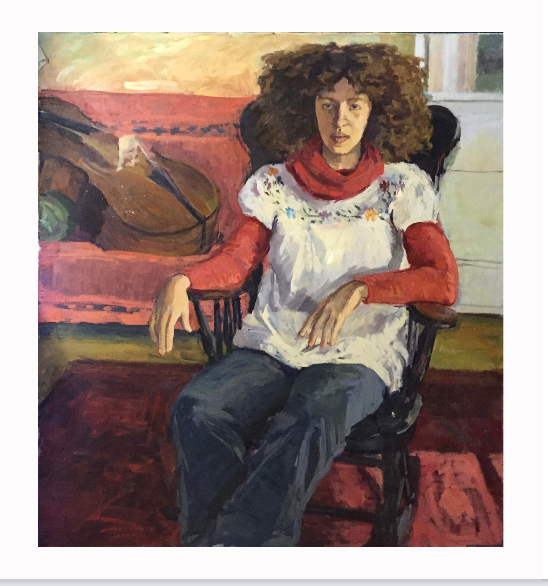 Woman with curly hair sitting in a chair, wearing a white top with red sleeves and a red scarf, in a room with a piano.