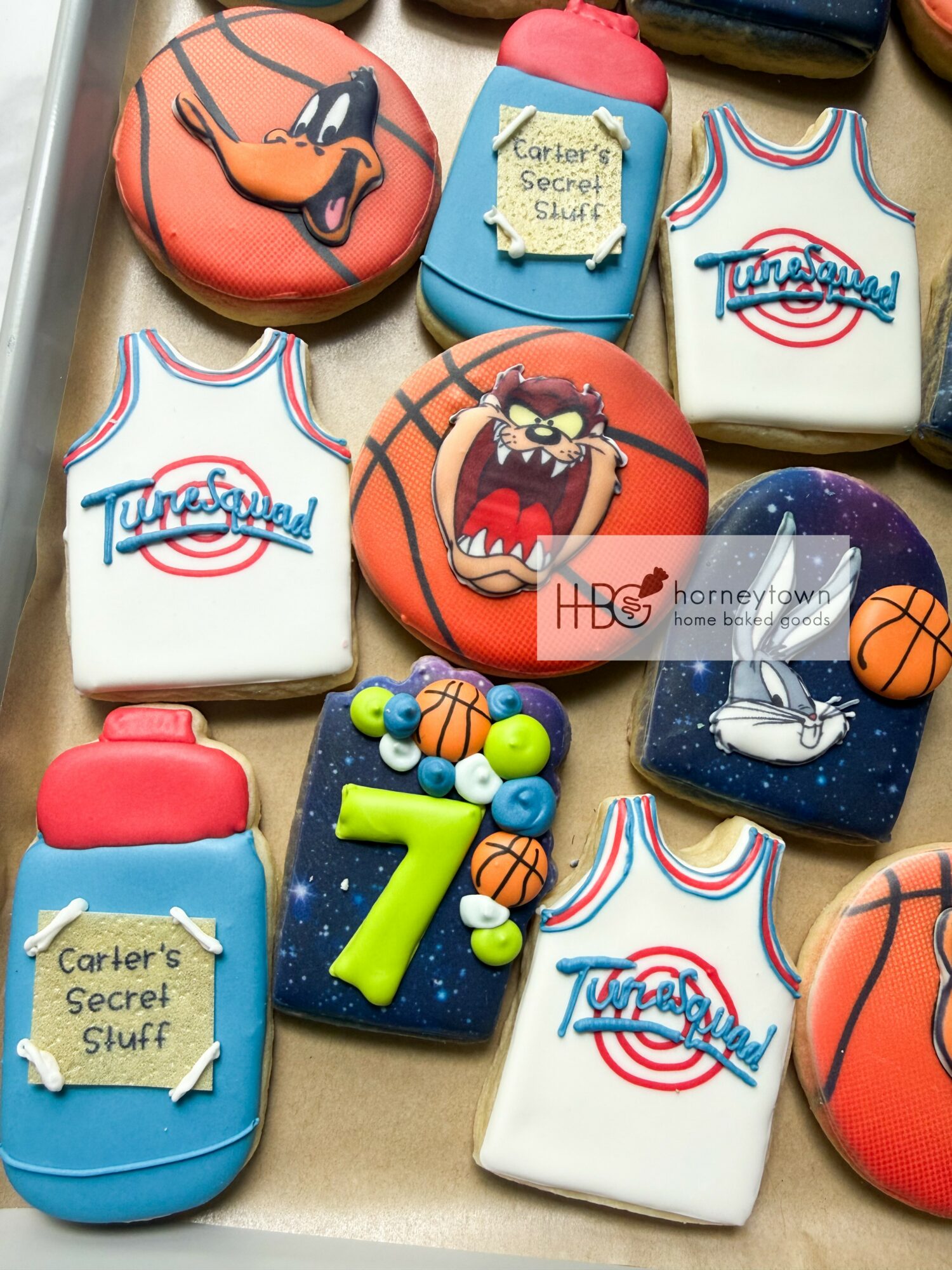 Decorated cookies with basketball, sports theme, and a blue bottle with a yellow number 7, on a tray.