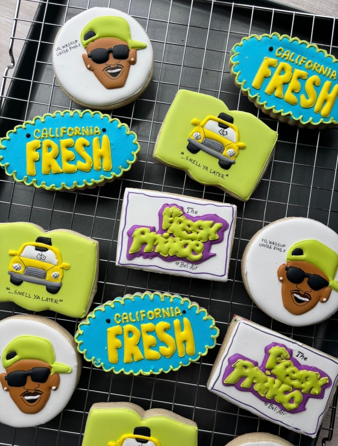 Cookies with California Fresh and Fuzzy Fuzz logos, and cartoon faces with sunglasses and green hair, on a wire grid.