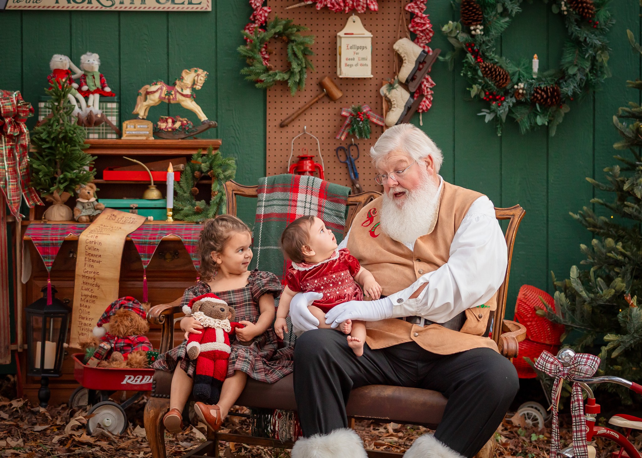 Santa Claus with children in a festive room decorated with wreaths, toys, and Christmas decorations.