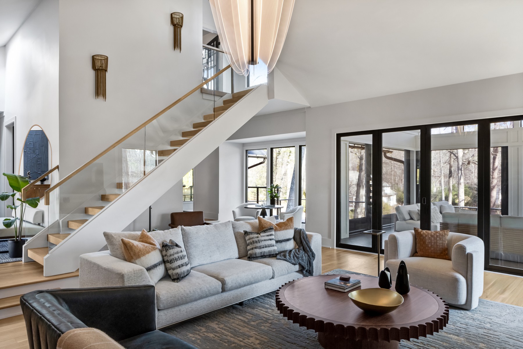 Living room with large sofa, armchair, round coffee table, and sliding glass doors, bright and modern interior.