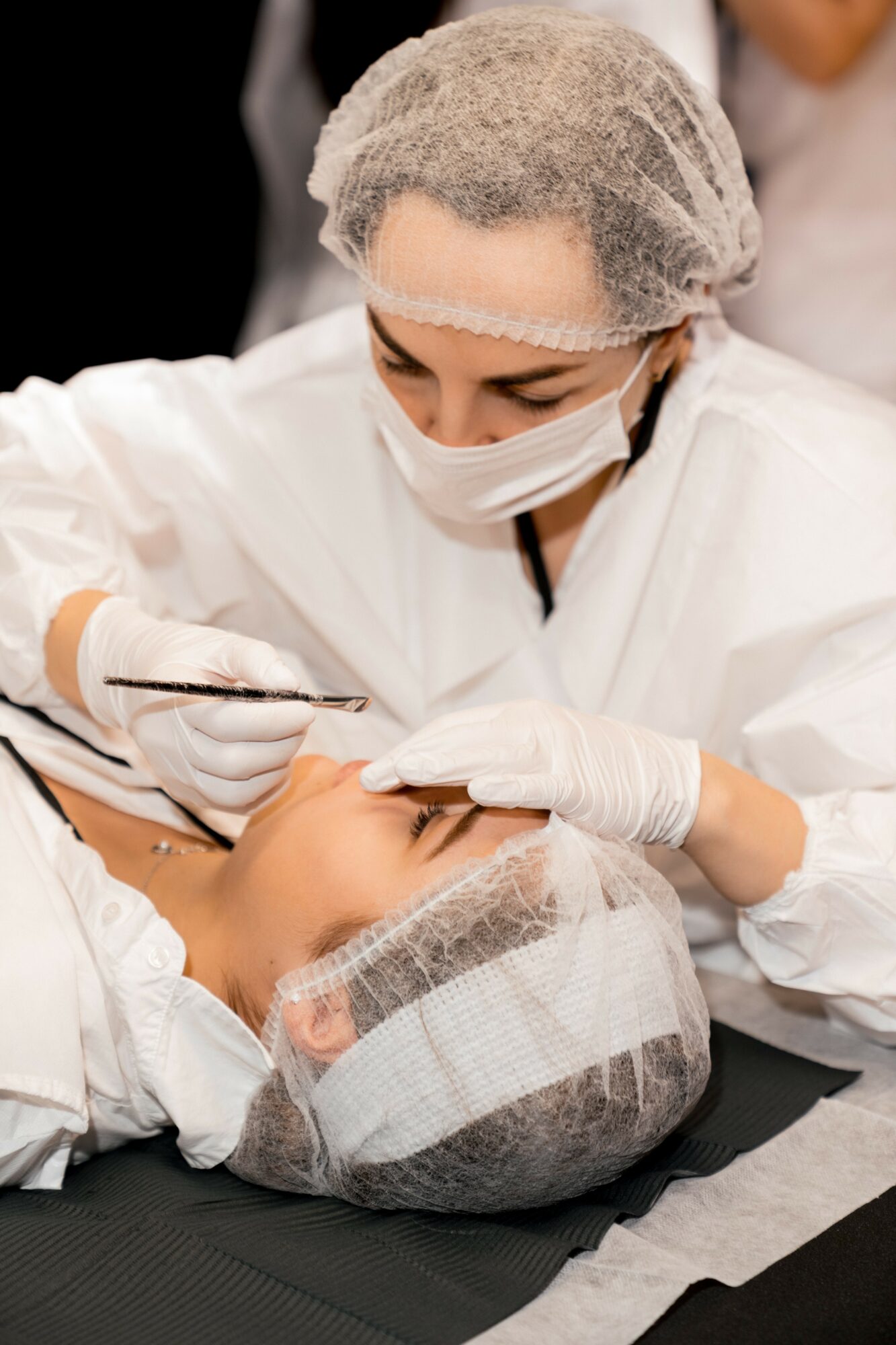 Medical professional in protective gear performs a procedure on a patient lying down.