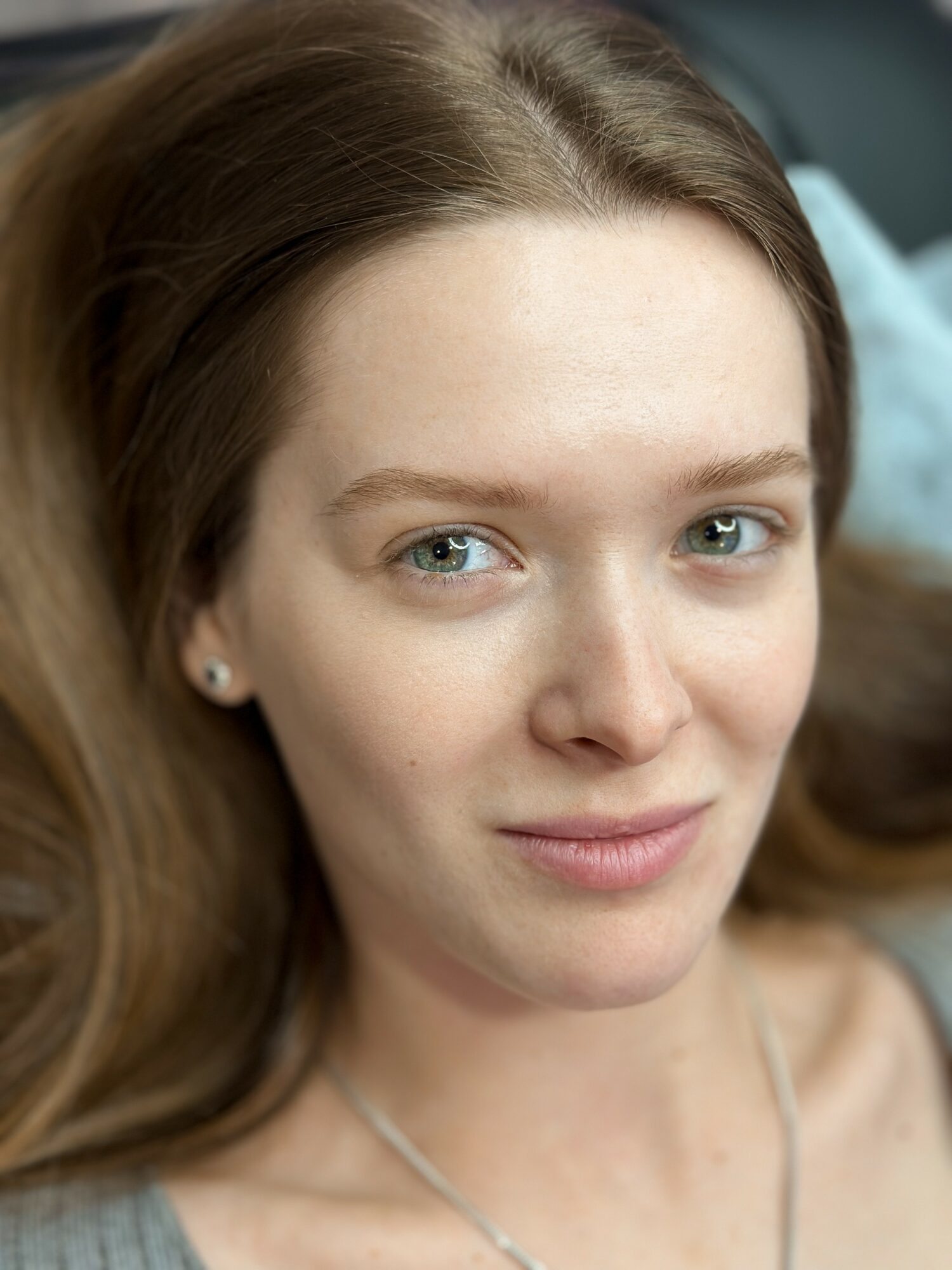 Close-up of a woman with light skin, blue eyes, and long brown hair, smiling softly.